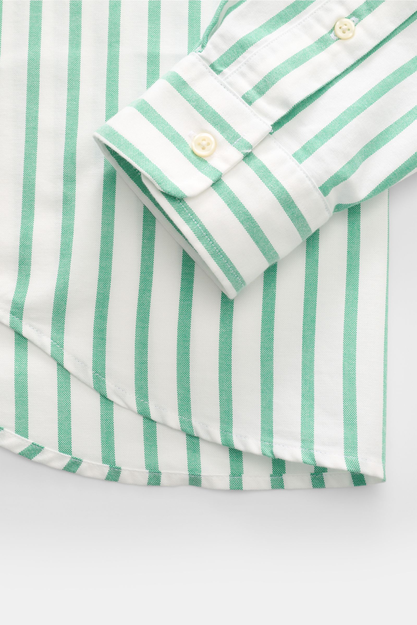 Close-up from above of the sleeve and lower hem of the Polo Ralph Lauren Casual Hemd Button-Down-Kragen grün/weiß gestreift, showcasing green and white vertical stripes, buttoned cuff, and rounded hem. Stilvoll durch den Sommer: Das Slim-Fit-Hemd von P