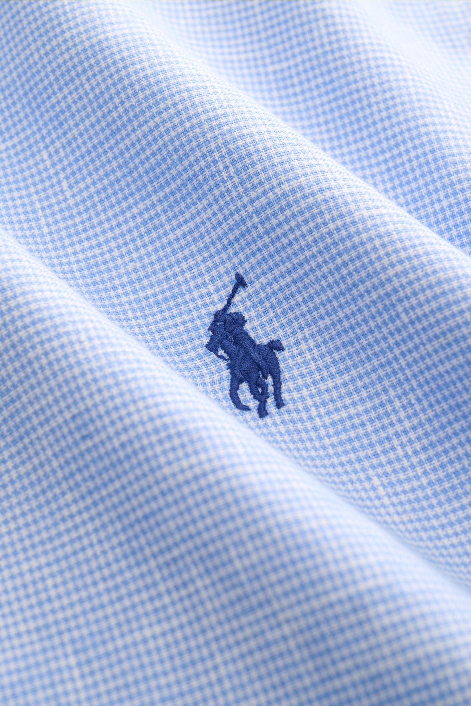 Close-up from a slightly angled perspective of Polo Ralph Lauren Oxford shirt shark collar light blue/white checked fabric with navy blue polo player logo embroidery.

Elegance for hot days: This shirt in linen and cotton by POLO RALPH LAUREN enhances 
