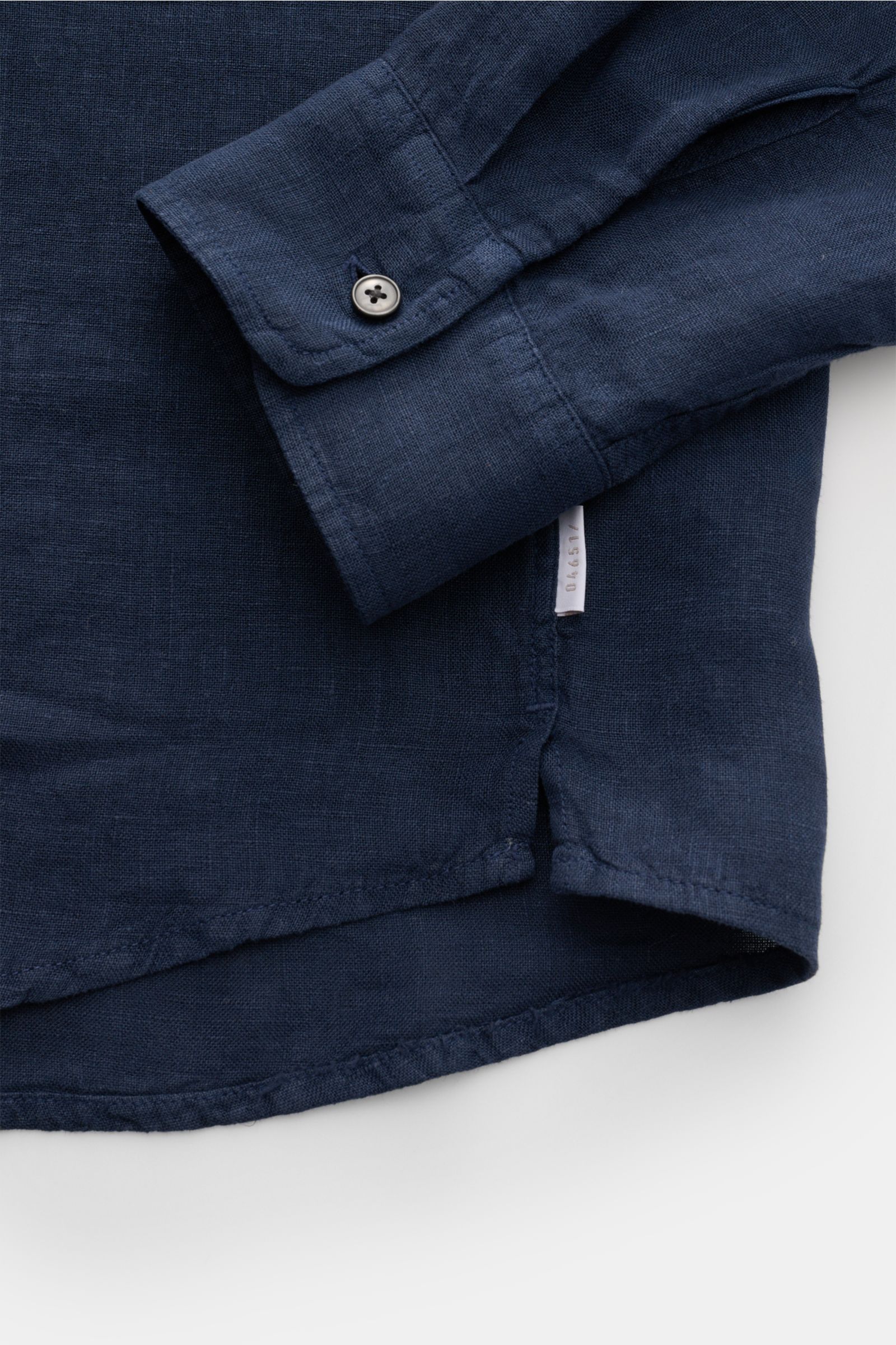 Close-up from above of the cuff and hem of the 04651/ A trip in a bag Leinenhemd schmaler Kragen navy made of pure linen with airy texture and classic details. 

Mühelose Leichtigkeit
