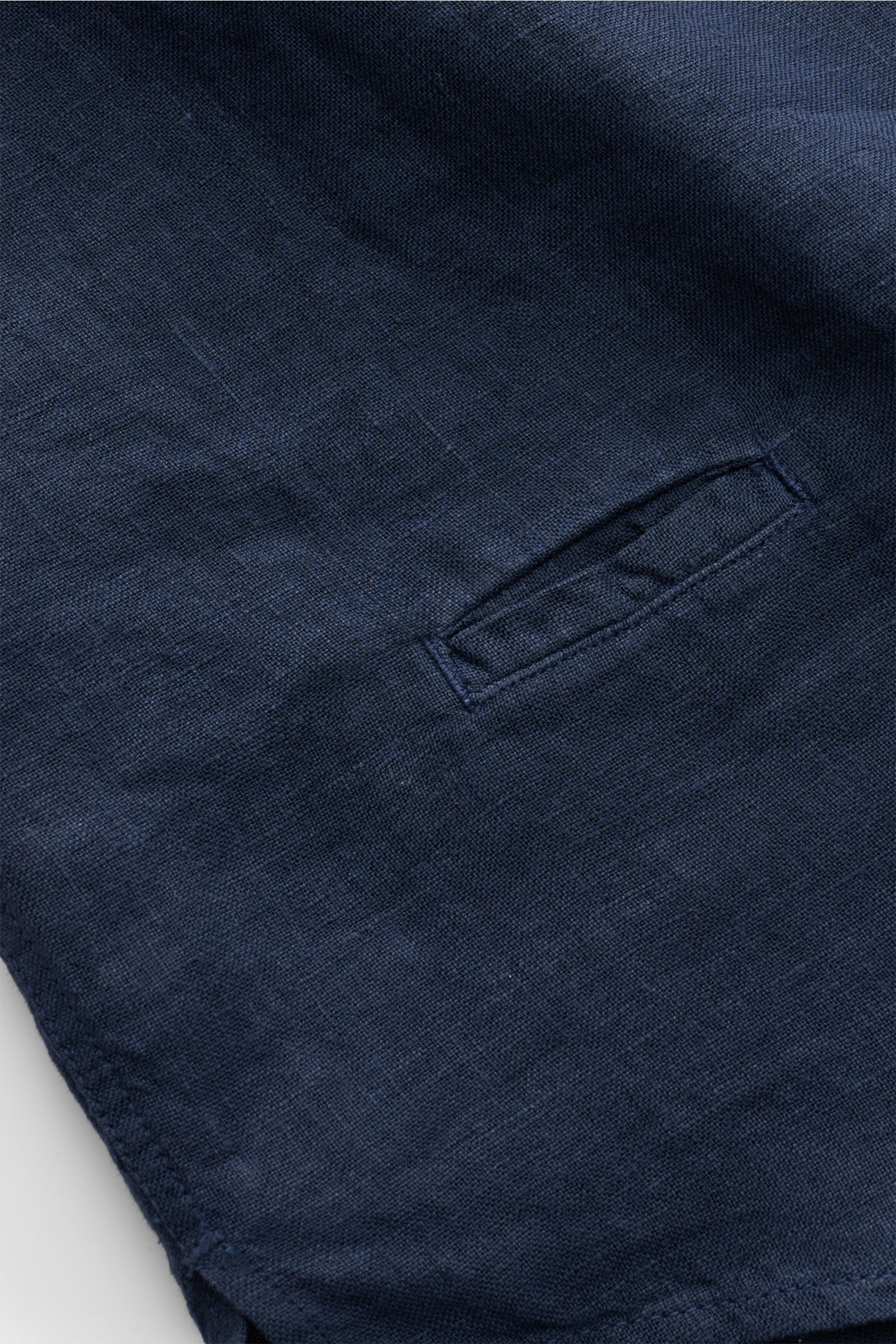 Close-up of navy linen fabric and pocket of 04651/ A trip in a bag Leinenhemd schmaler Kragen navy, showing texture and stitching.

Mühelose Leichtigkeit