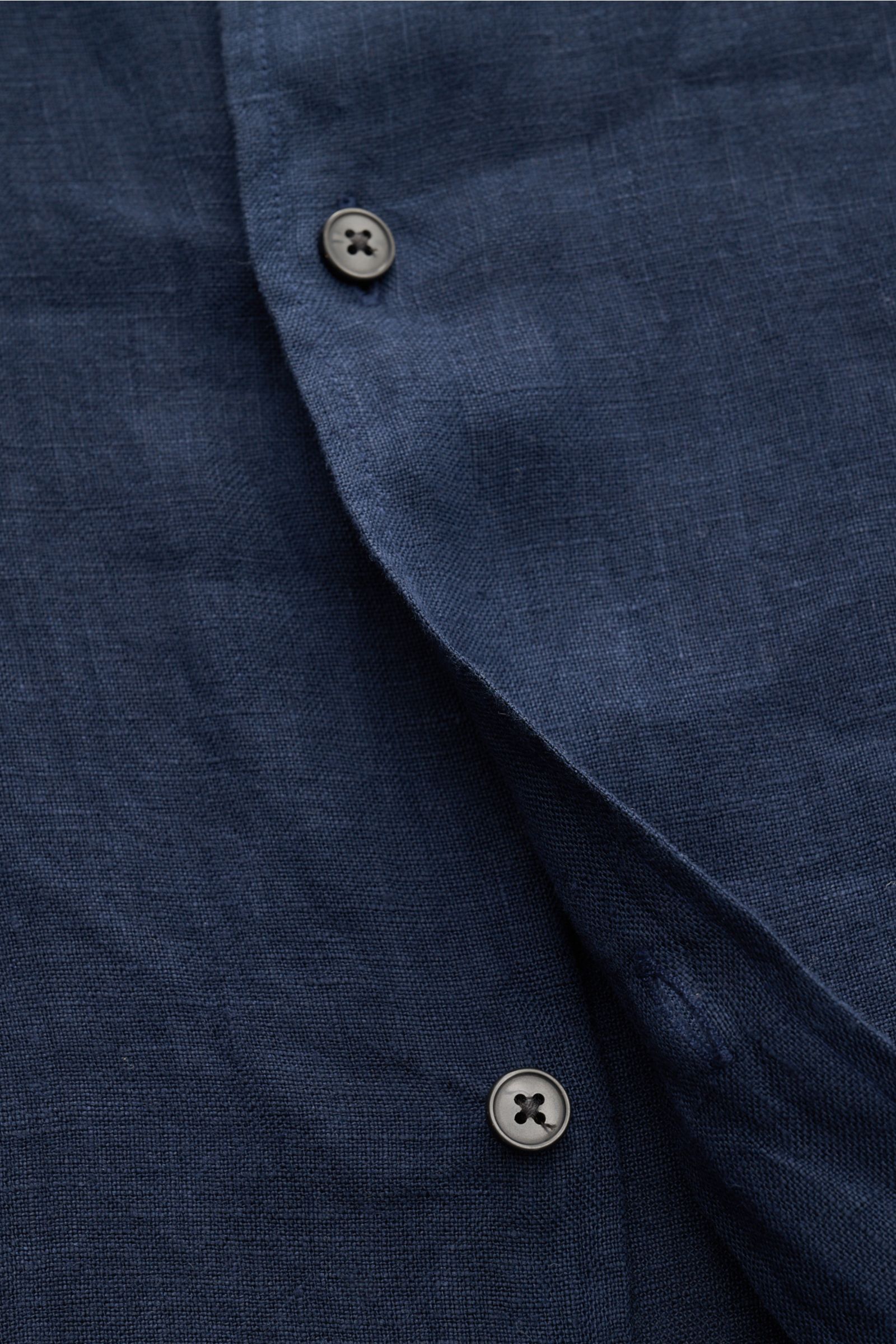 Close-up front view of 04651/ A trip in a bag Leinenhemd schmaler Kragen navy linen shirt showing button and fabric texture, pure linen, airy feel, regular fit.

Mühelose Leichtigkeit