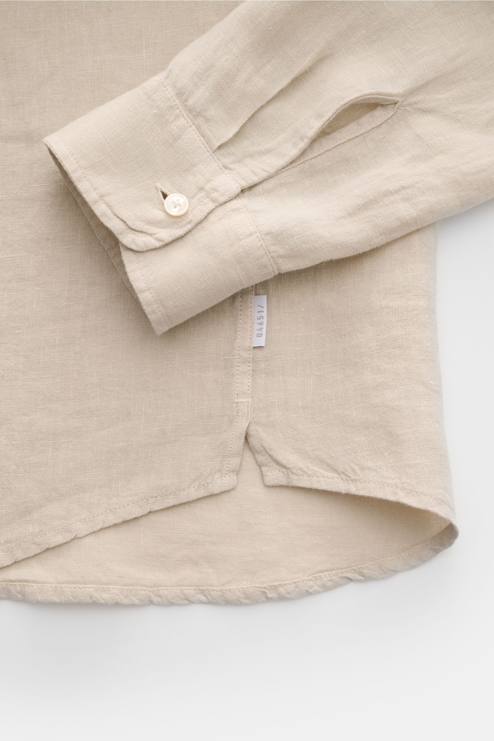 Close-up view of the cuff and hem of the 04651/ A trip in a bag Leinenhemd schmaler Kragen sand shirt, showing its fine linen texture and subtle stitching.

Mühelose Leichtigkeit