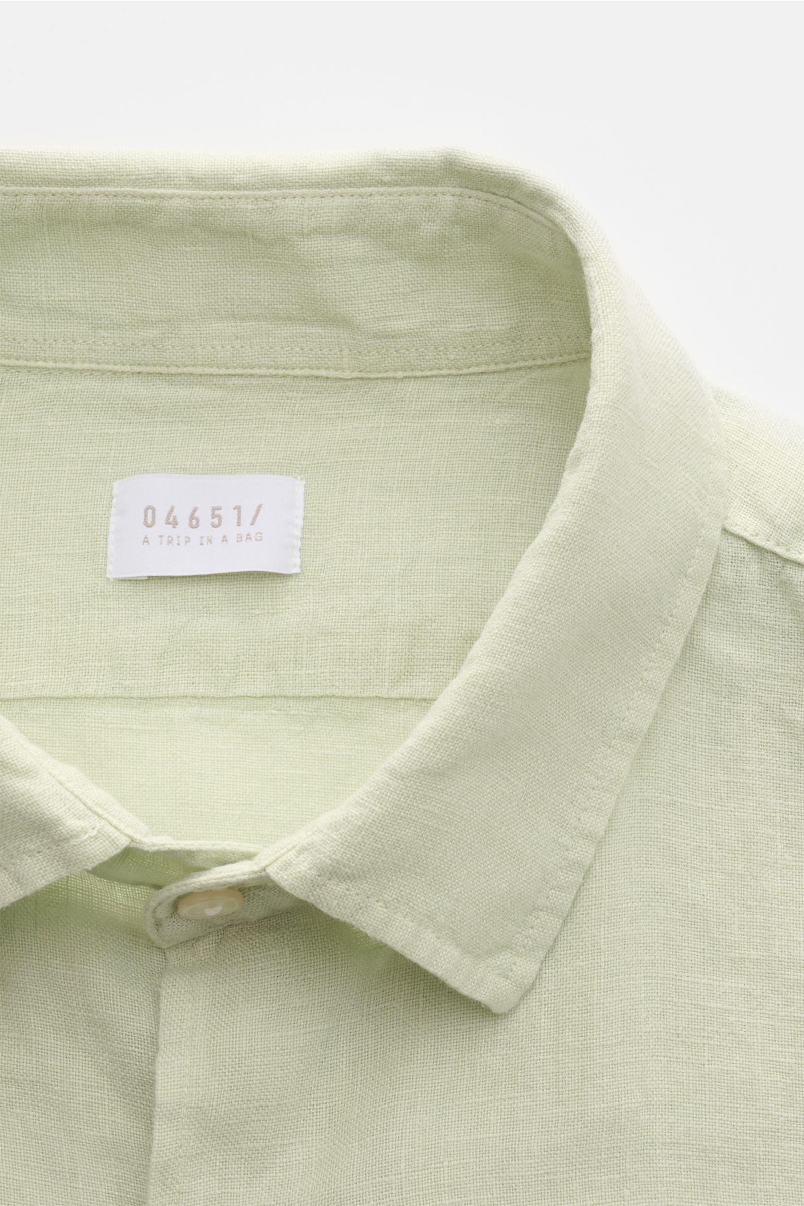 Close-up front view of the pastel green 04651/ A trip in a bag Leinenhemd schmaler Kragen pastellgrün, a pure linen shirt with a narrow collar, visible fabric texture, and a French button placket. Mühelose 