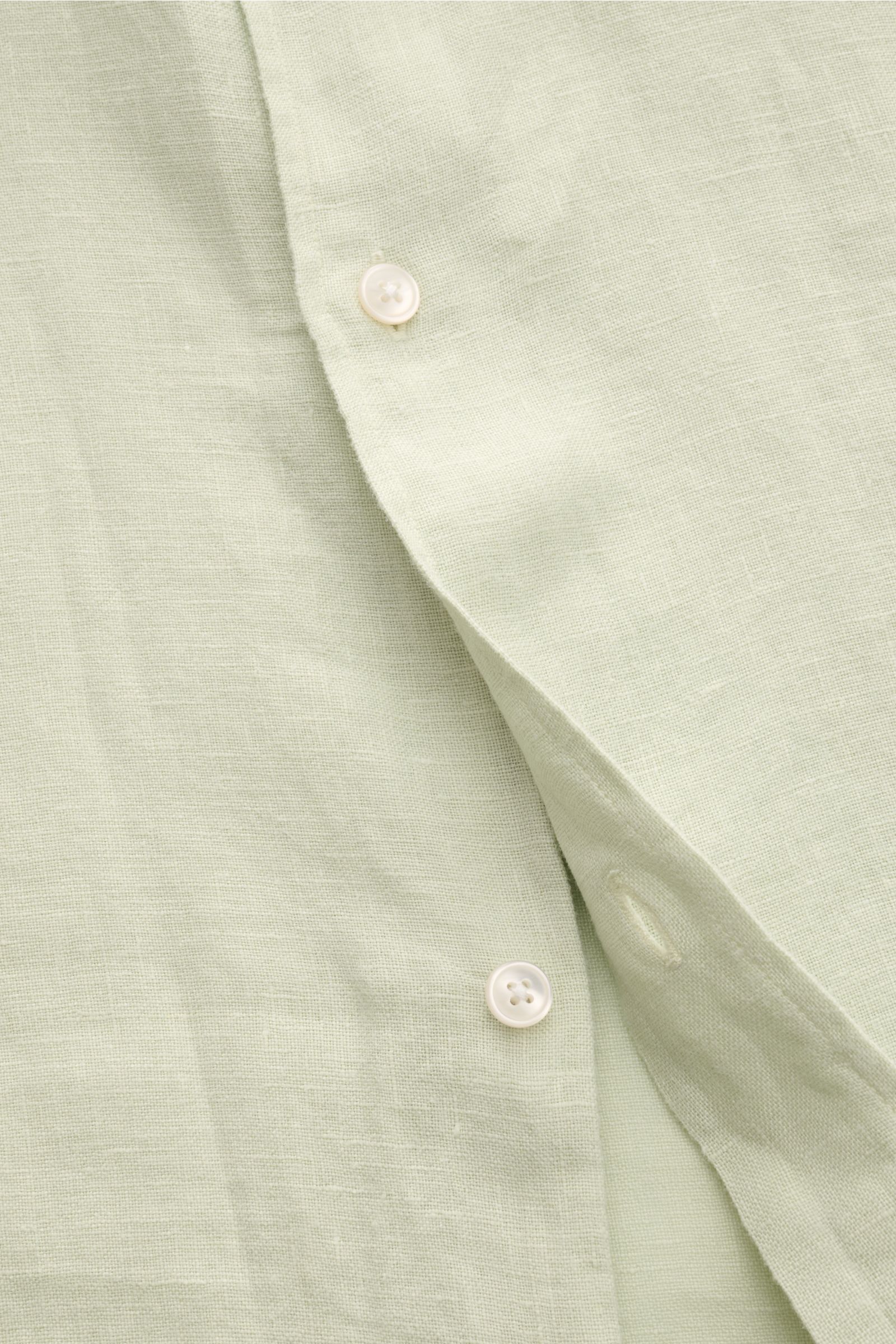 Close-up front view of 04651/ A trip in a bag Leinenhemd schmaler Kragen pastellgrün, showing pastel green linen fabric with buttons and texture. Mühelose Leichtigkeit