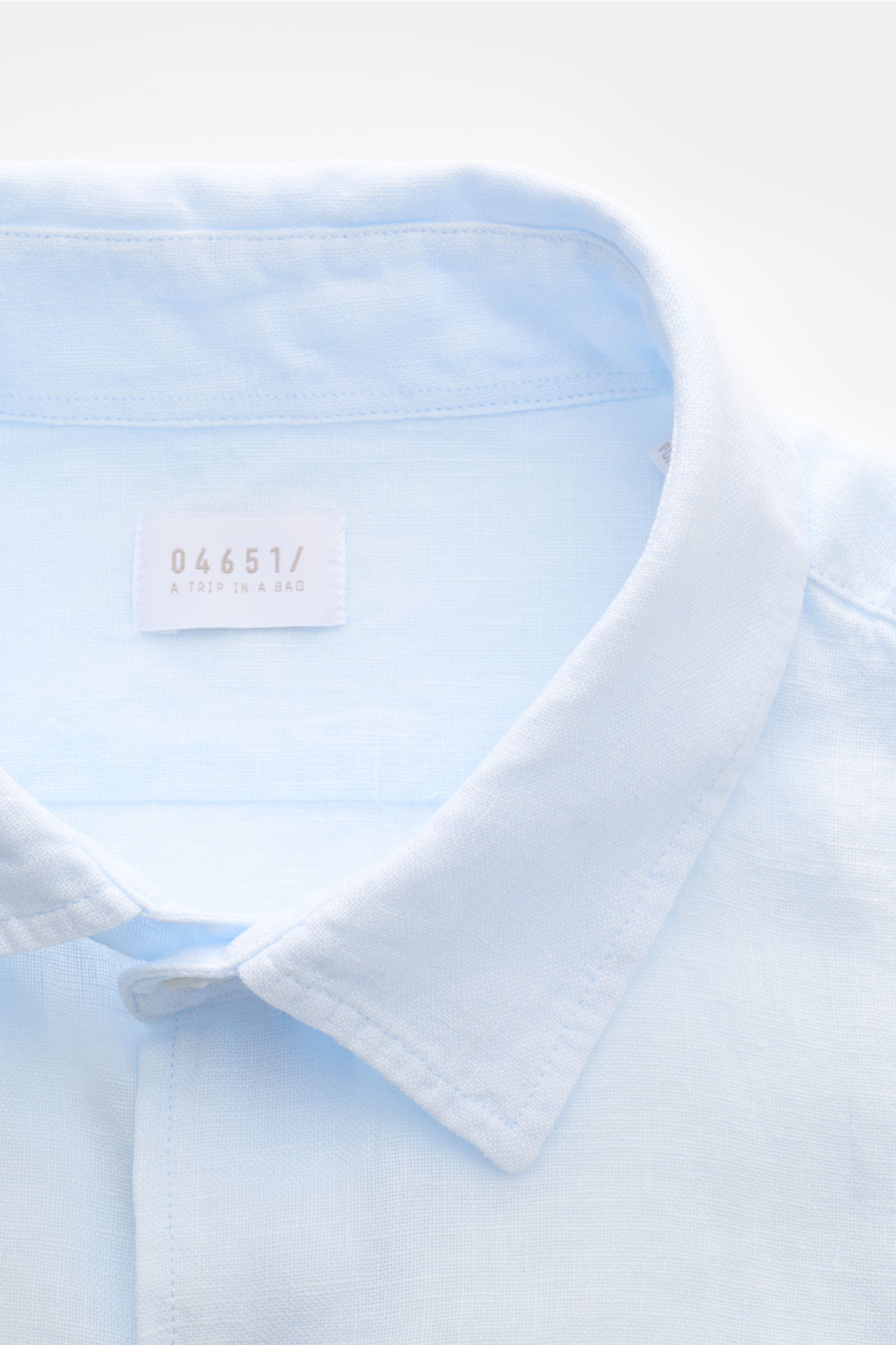 Close-up front view of 04651/ A trip in a bag Leinenhemd schmaler Kragen pastellblau, a pastel blue pure linen shirt with a narrow collar, showcasing fine texture and stitching. Mühelose 