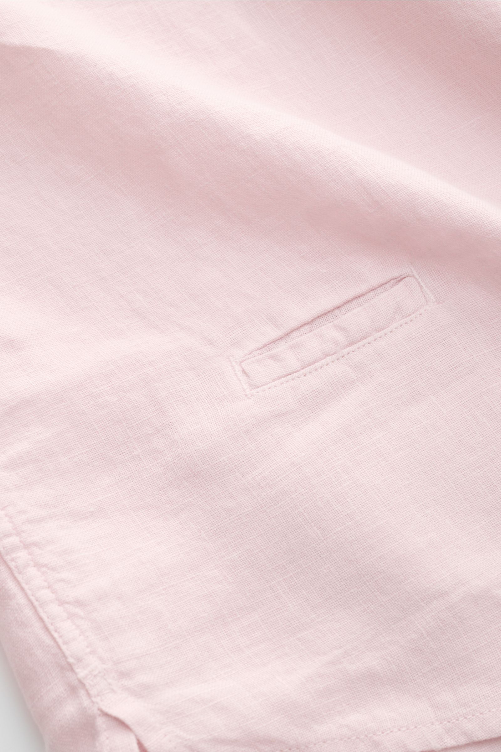 Close-up front view of the 04651/ A trip in a bag Leinenhemd schmaler Kragen rosé, showcasing the pure linen fabric, airy texture, narrow collar, French placket, classic sports cuff, small side seam label, slightly rounded hem, and short side slits. 