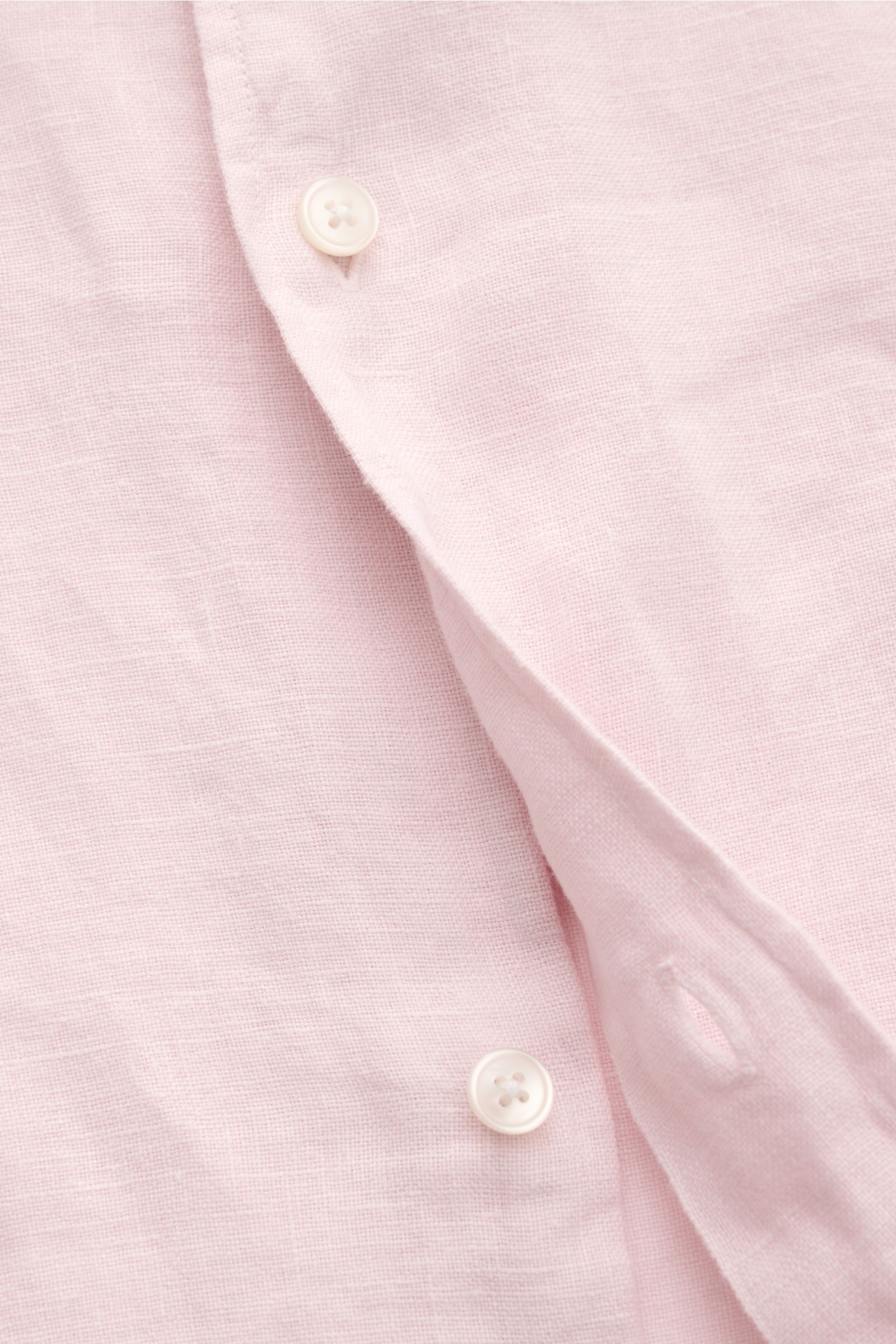 Close-up front view of 04651/ A trip in a bag Leinenhemd schmaler Kragen rosé, a light pink linen shirt with fine texture, narrow collar, and white buttons. Mühelose Leichtigkeit