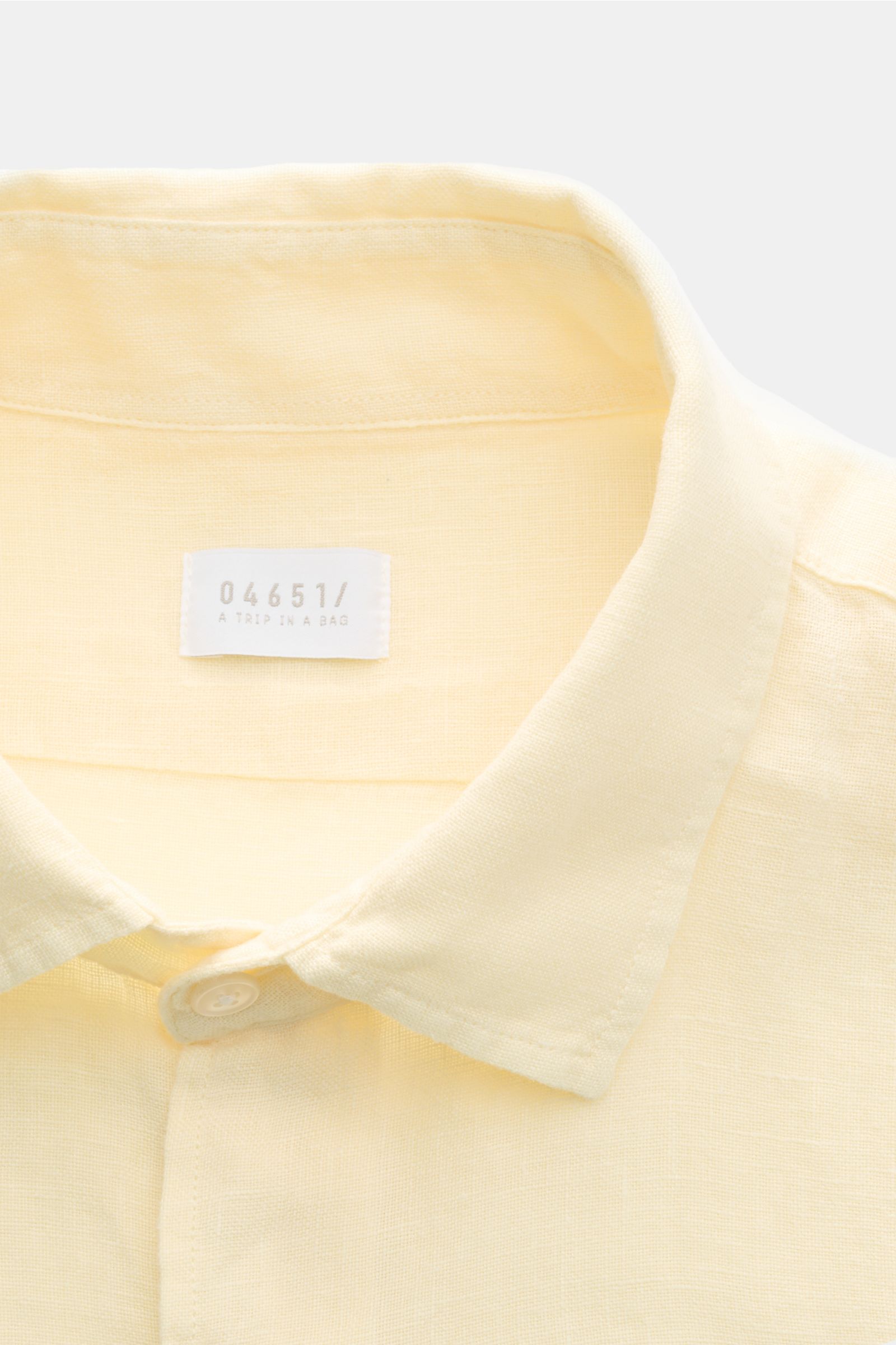 Close-up front view of the 04651/ A trip in a bag Linen shirt narrow collar pastel yellow showing its narrow collar, French button placket, and pure linen texture. 

Effortless lightnes