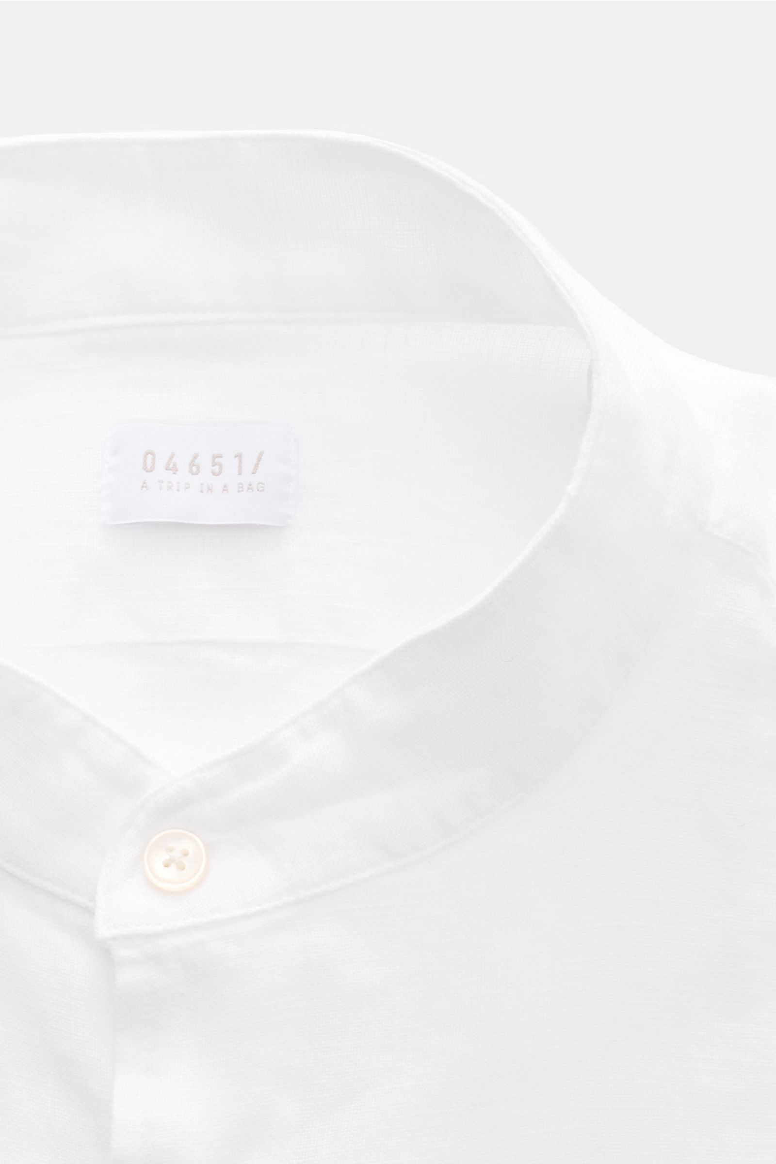 Close-up front view of 04651/ A trip in a bag Linen shirt 'Linen Guru' grandad collar white showing soft pure linen fabric and single button.

Description: Summer for your skin: The airy casual shirt 'Linen Guru' by 04651/ A TRIP IN A BAG is made of pu