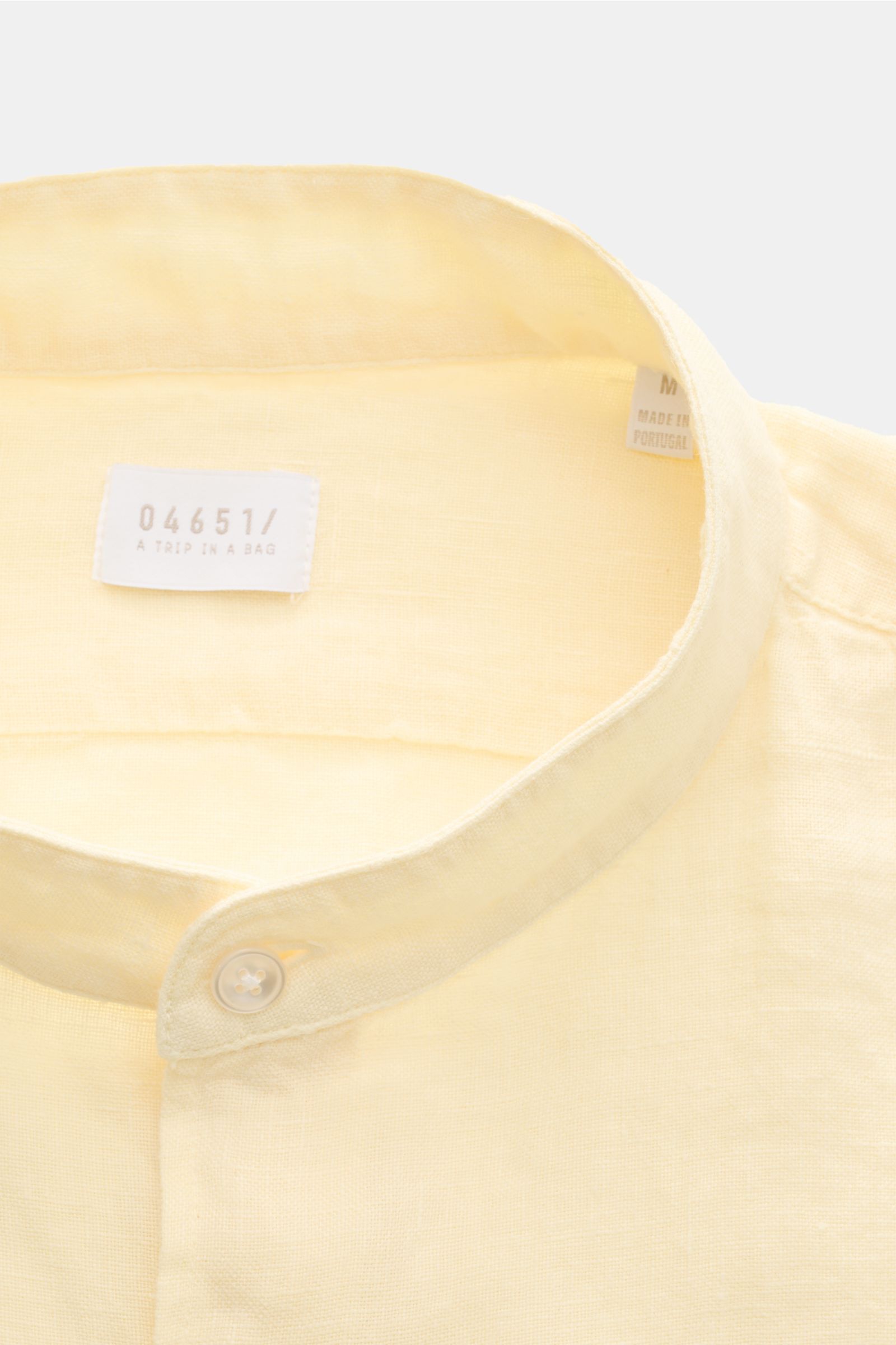 Close-up front view of 04651/ A trip in a bag Linen shirt 'Linen Guru' grandad collar pastel yellow, showcasing its pure linen fabric and grandad collar. Summer for your skin: The airy casual shirt 'Linen Guru' by 04651/ A TRIP IN A BAG is made of pure li
