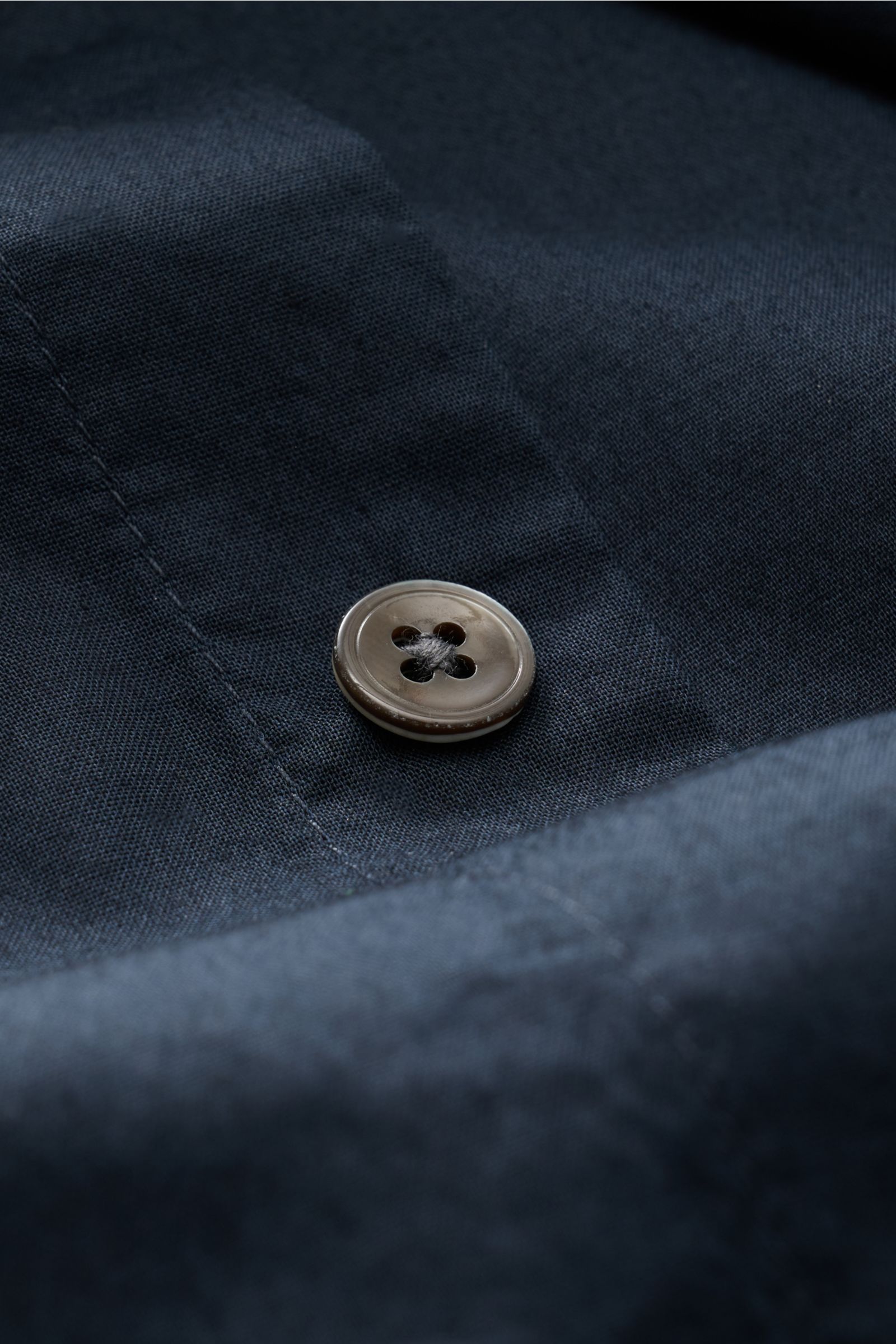 Alt tag (124 characters):
Close-up front view of a button on navy fabric showing texture of 04651/ A trip in a bag Casual shirt 'Cloudy Shirt' slim collar navy.

Description:
Lightweight and comfortable for hot days: The c