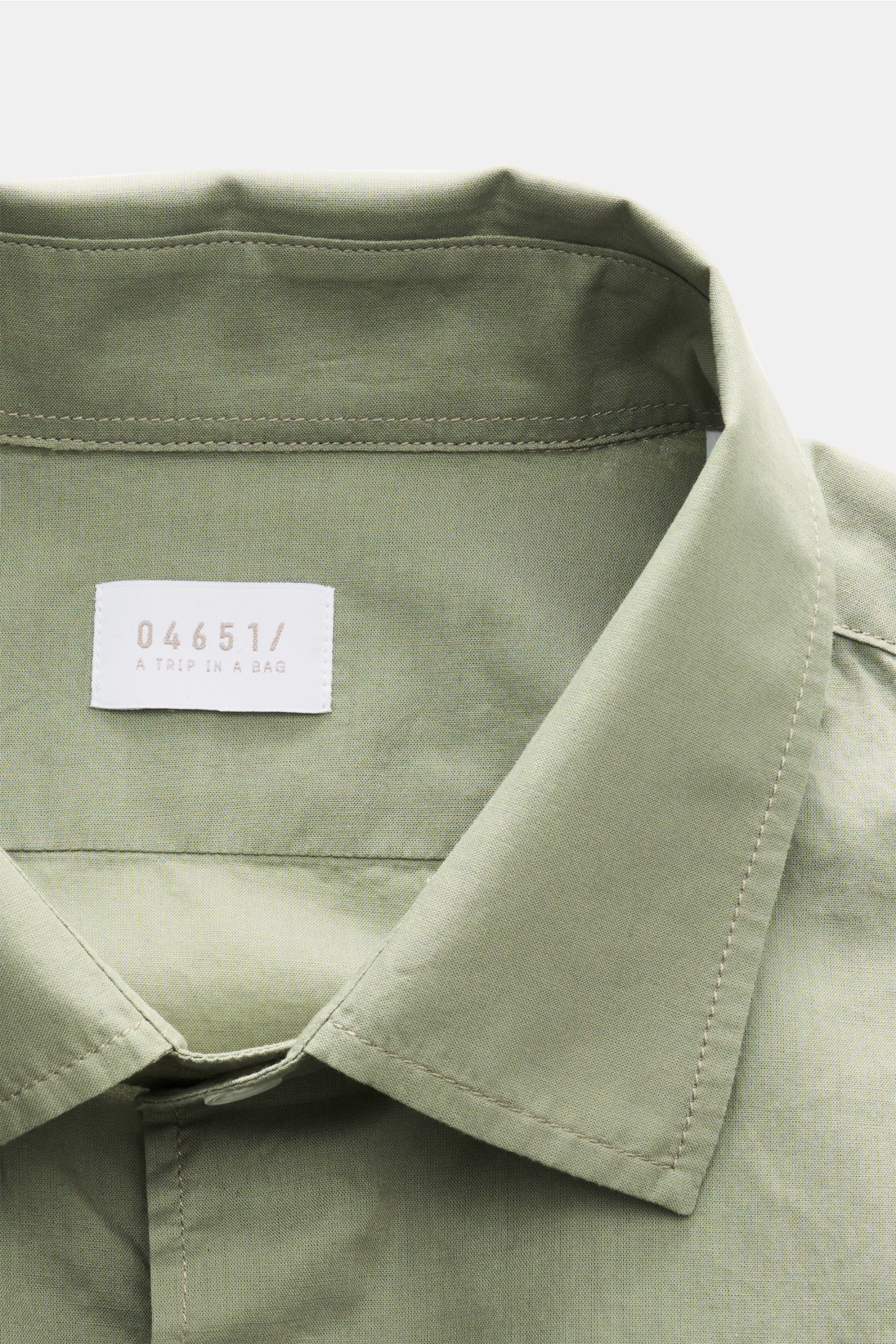 Close-up front view of the slim collar on the 04651/ A trip in a bag Casual shirt 'Cloudy Shirt' slim collar sage in light green cotton.

Lightweight and comfortable for hot days: The casual shirt 'Cloudy Shirt' by 04651/ 