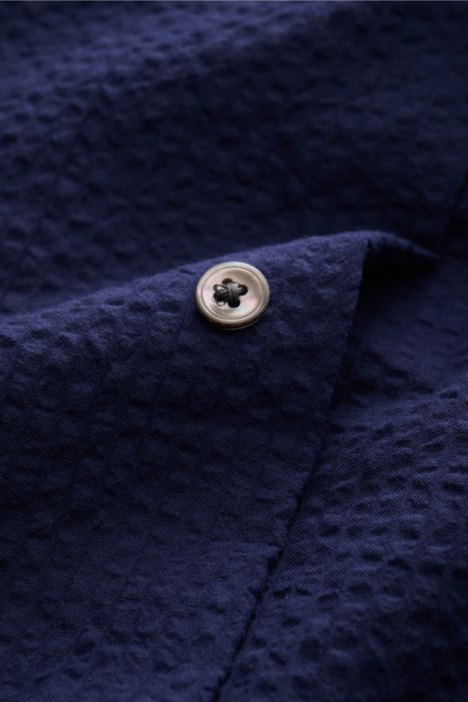 Close-up view of the navy seersucker fabric and button detail on the 04651/ A trip in a bag Seersucker shirt Kent collar navy, showcasing its textured cotton material.

Effortlessly cas