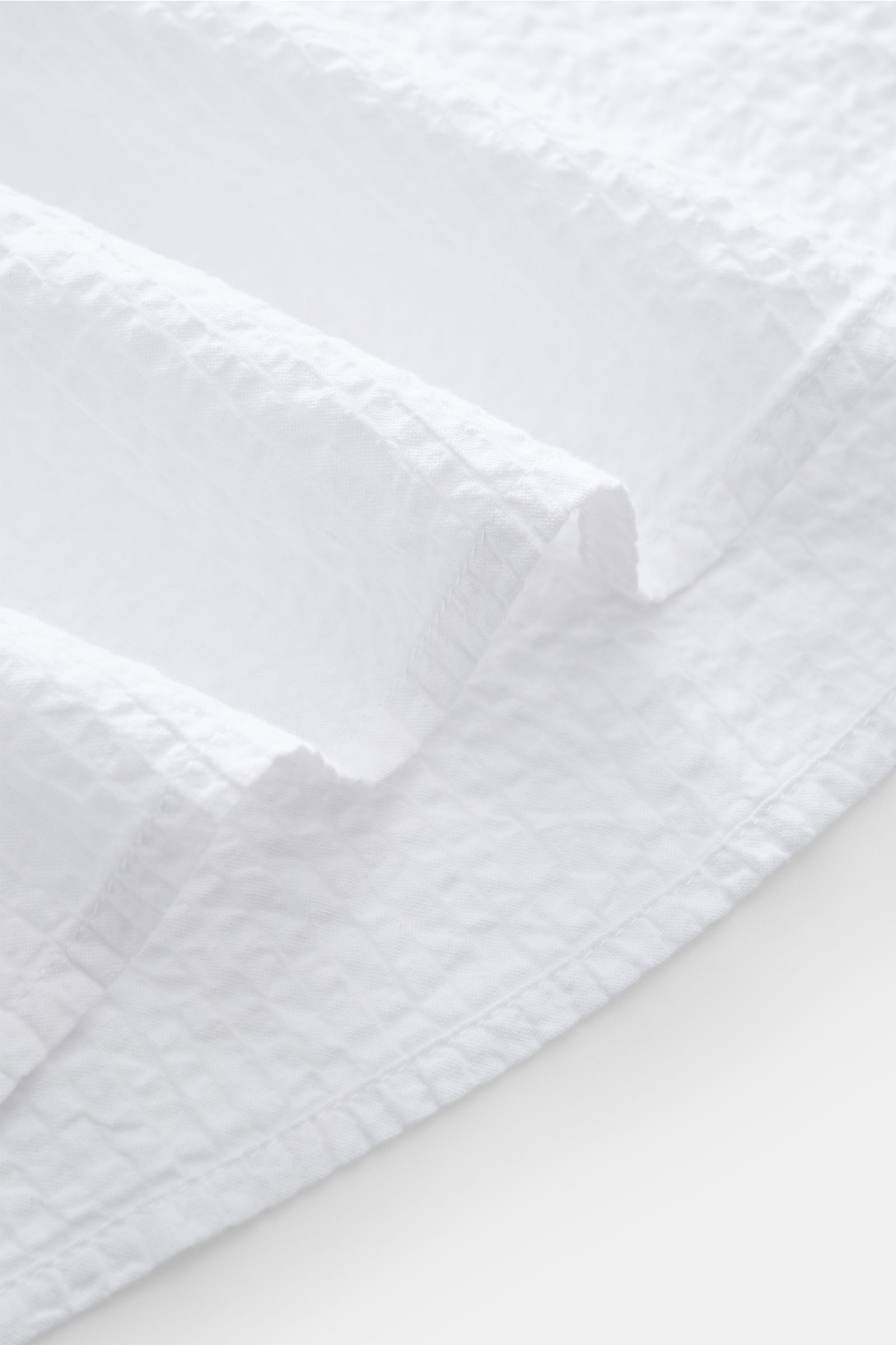 Close-up fabric detail of the 04651/ A trip in a bag Seersucker shirt Kent collar white, showing textured pure cotton seersucker from a top-down perspective.

Effortlessly casual