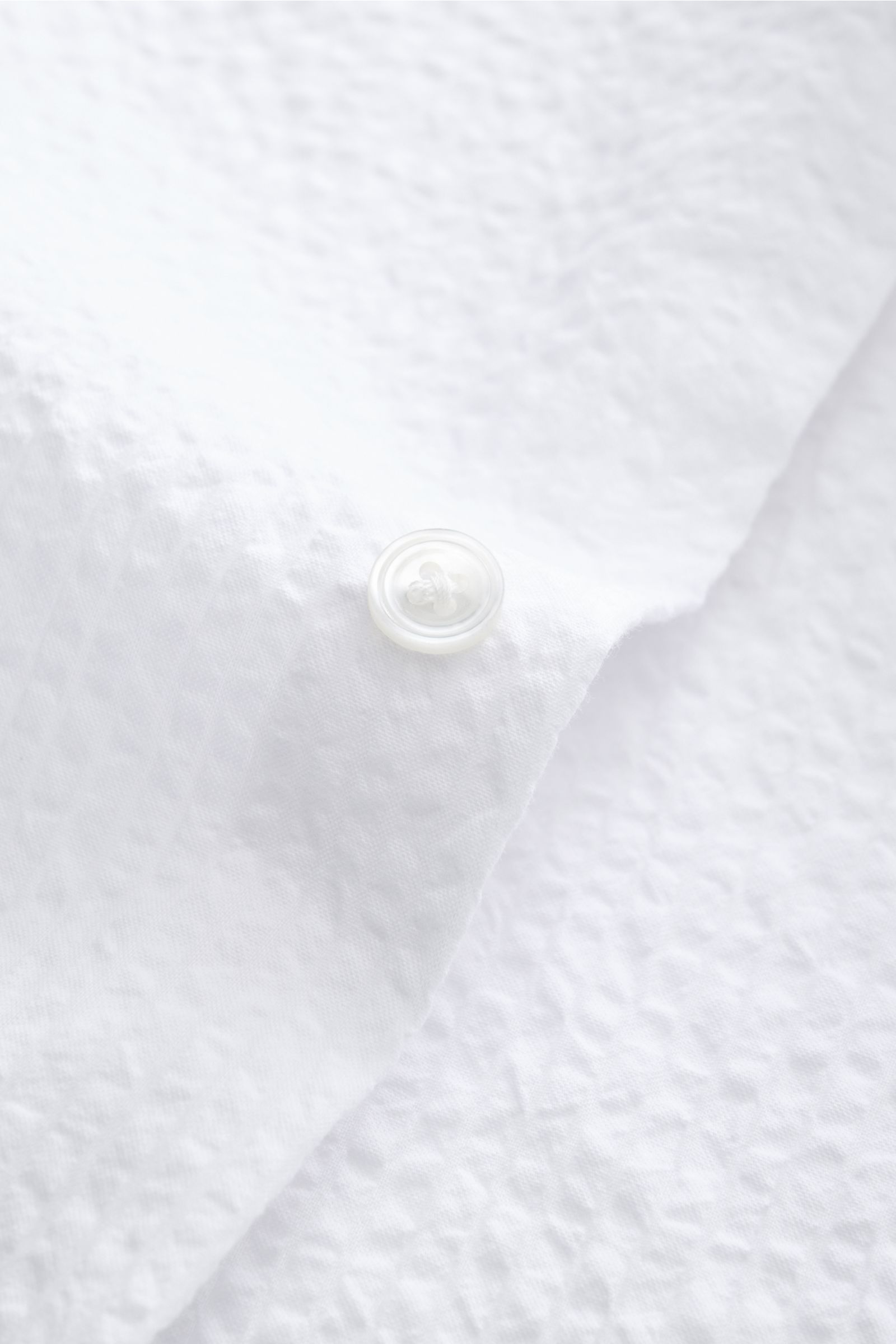 Close-up view of the white seersucker fabric and button on the cuff of the 04651/ A trip in a bag Seersucker shirt Kent collar white.

Effortlessly casual