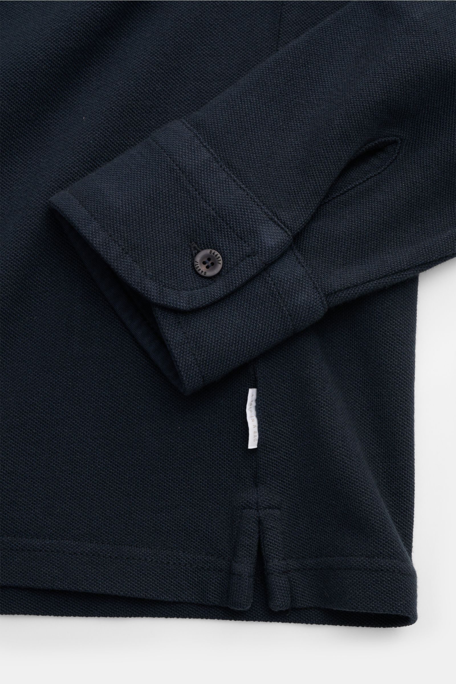 Close-up front view of the 04651/ A trip in a bag Piqué shirt slim collar navy showing the folded cuff with a button and side hem details.

Casual everyday basic by 04651/ A TRIP IN A BAG: This casual shirt in pure cotton piqué has an attractive relaxe