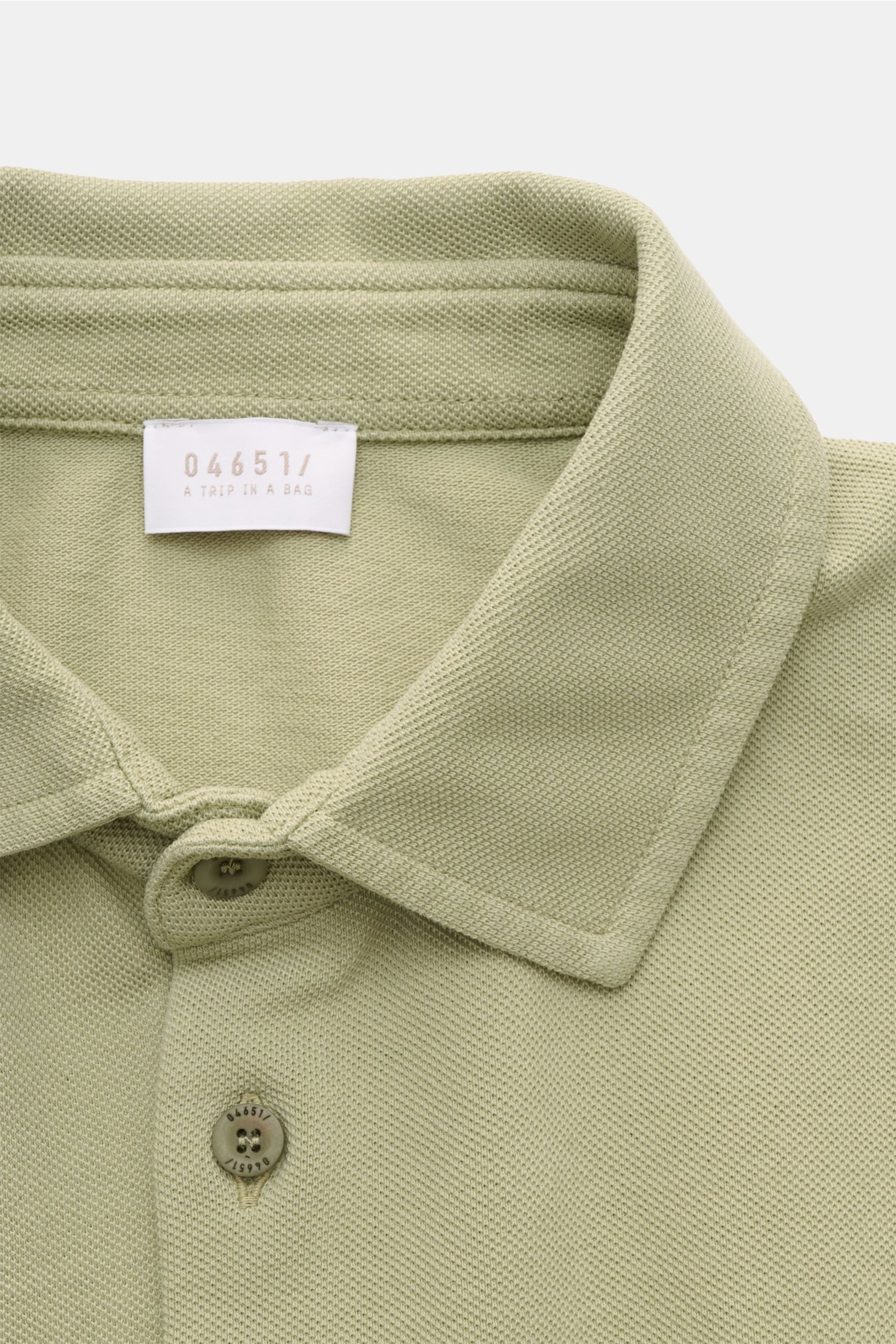 Close-up front view of the collar and buttons of the 04651/ A trip in a bag Piqué shirt slim collar sage in pure cotton piqué with garment-dyed fabric, narrow collar, French button placket, and fine texture. 

Casual everyday basic by 04651/ A TRIP IN 