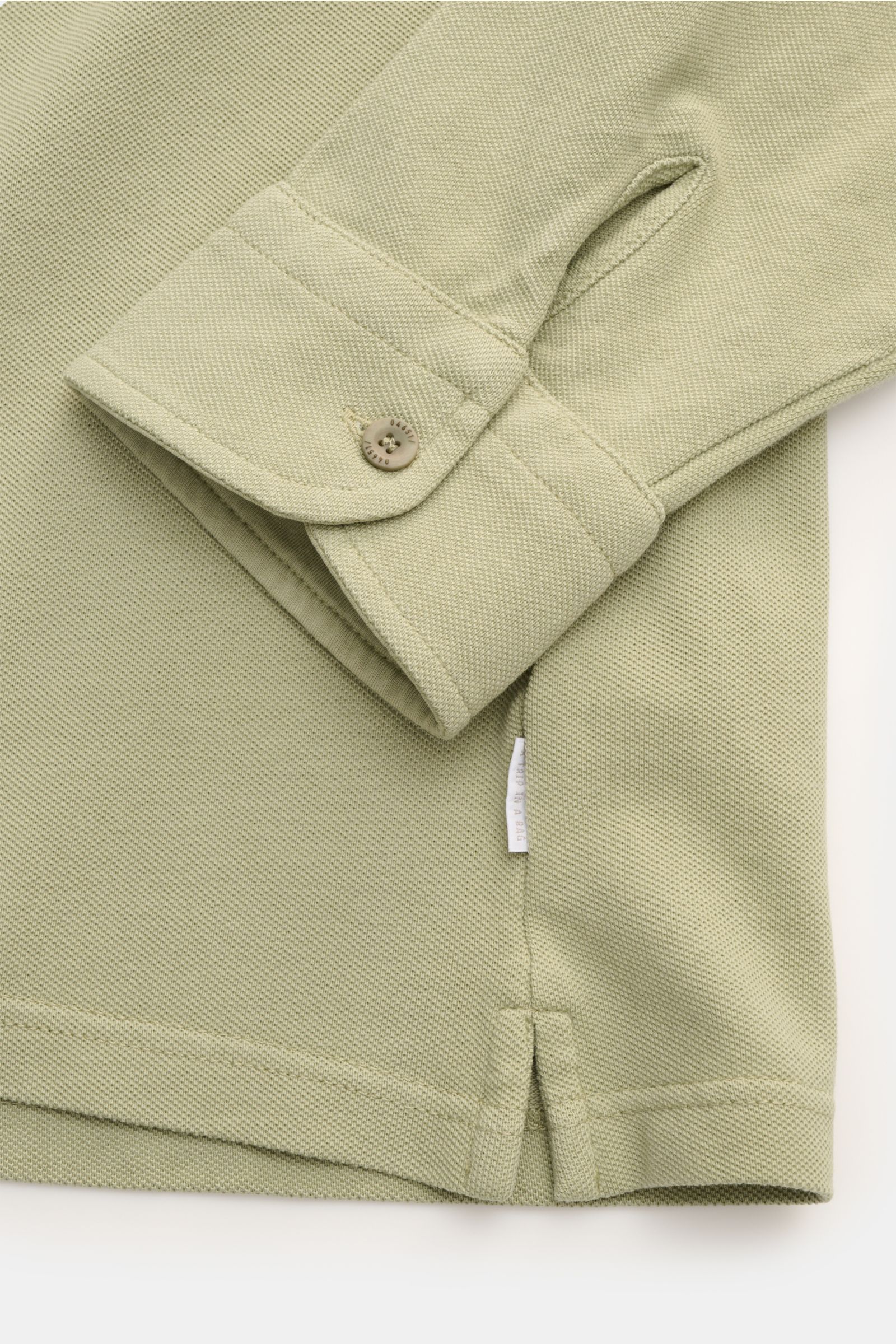 Close-up front view of 04651/ A trip in a bag Piqué shirt slim collar sage in pure cotton piqué, showing cuff, hem vents, and woven label.

Casual everyday basic by 04651/ A TRIP IN A BAG: This casual shirt in pure cotton piqué has an attractive relaxe