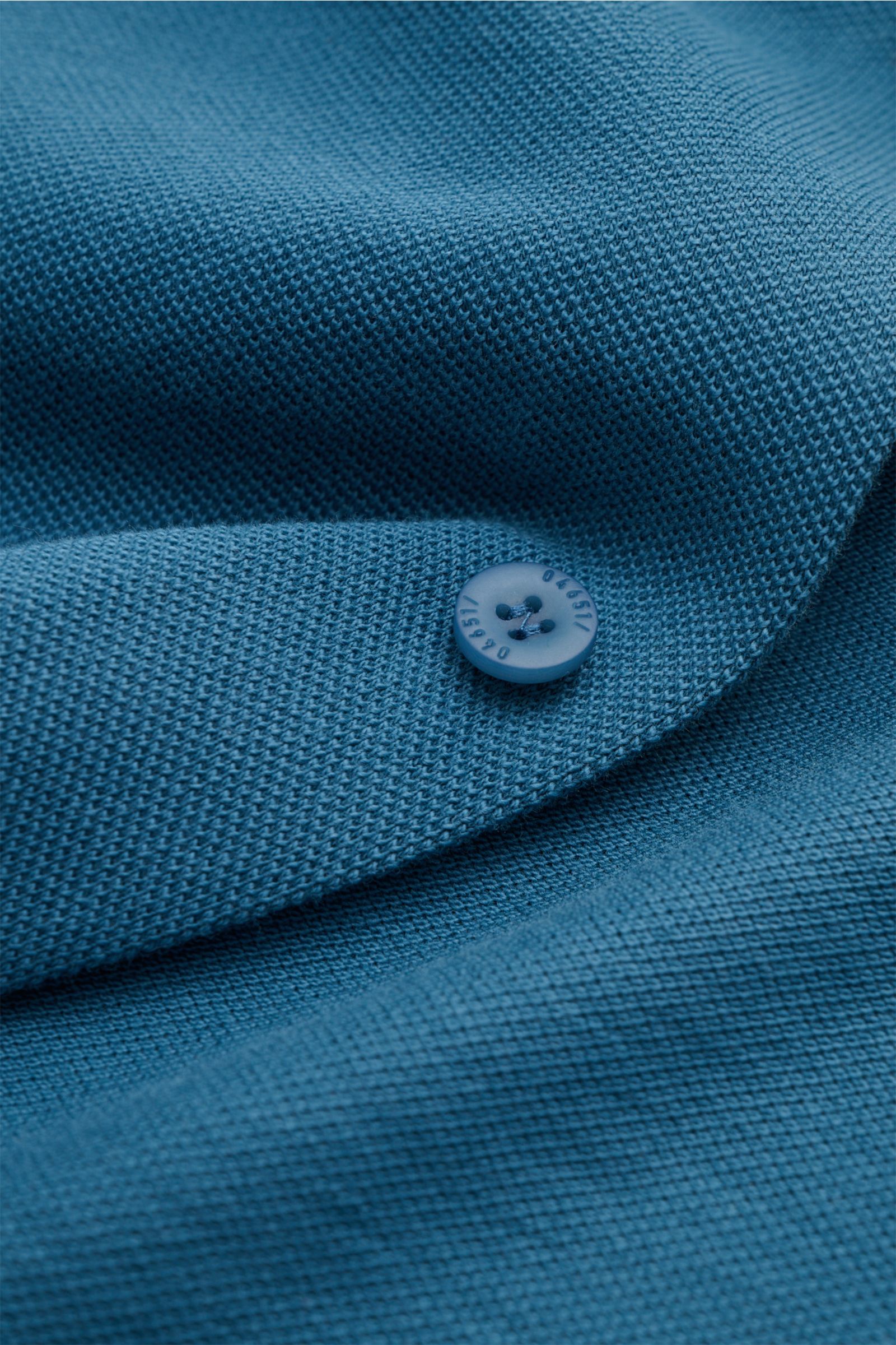 Close-up view of the textured fabric and button of the 04651/ A trip in a bag Piqué shirt slim collar teal, showing pure cotton piqué with a relaxed fit.

Description: Casual everyday basic by 04651/ A TRIP IN A BAG: This casual shirt in pure cotton pi
