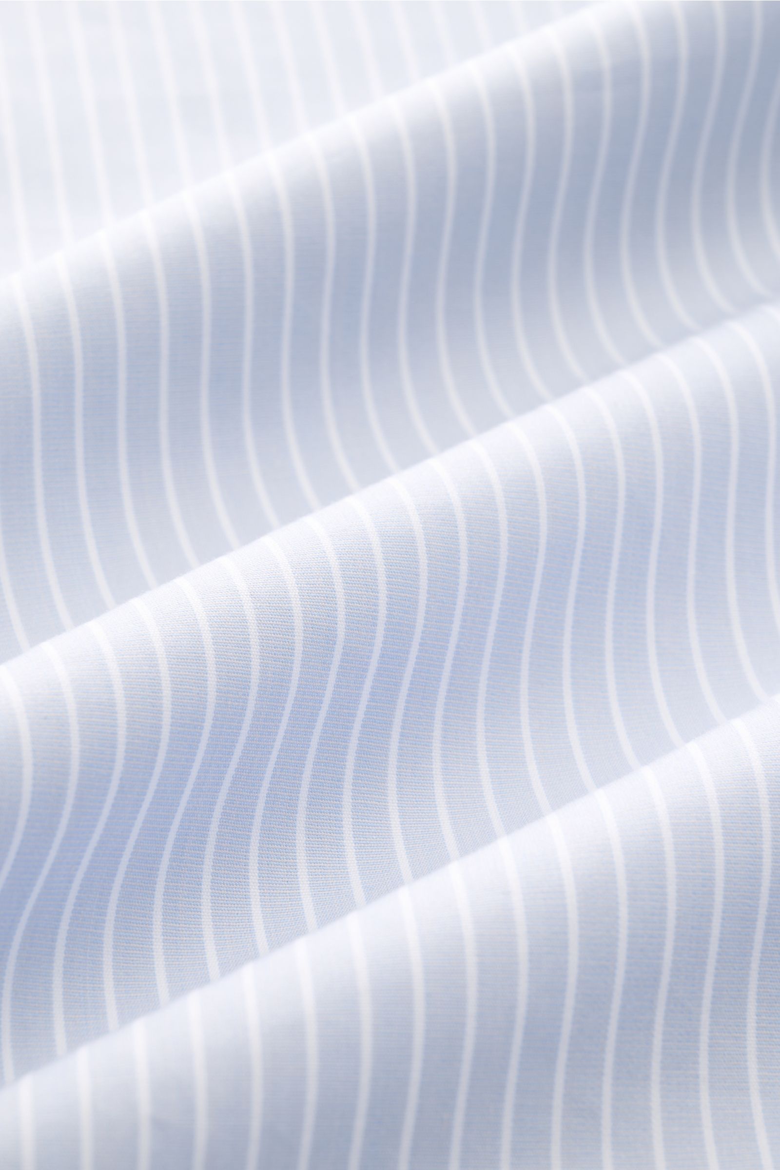 A close-up front-side view of A.P.C. Casual Hemd 'Malo' Kent-Kragen hellblau/weiß gestreift fabric showing light blue and white stripes, pure cotton, smooth feel, oversized fit, classic Kent collar, French button placket, classic sport cuffs, and slightly