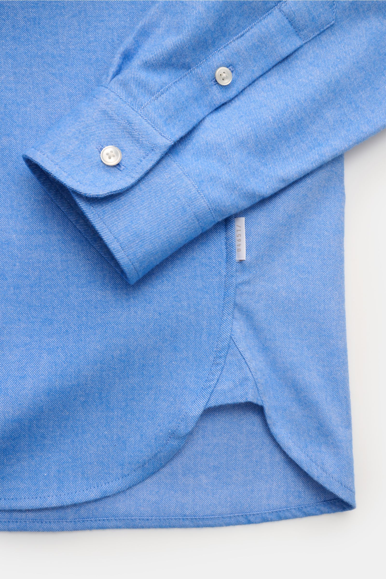 Close-up from above of the cuff and hem of the 04651/ A trip in a bag Flanellhemd Button-Down-Kragen blau meliert, made of soft pure cotton. Exklusiver Tragekomfort für die Übergangszeit: Das Flanellhemd aus der 'Look of the Games' Capsule von 04651/ A TR