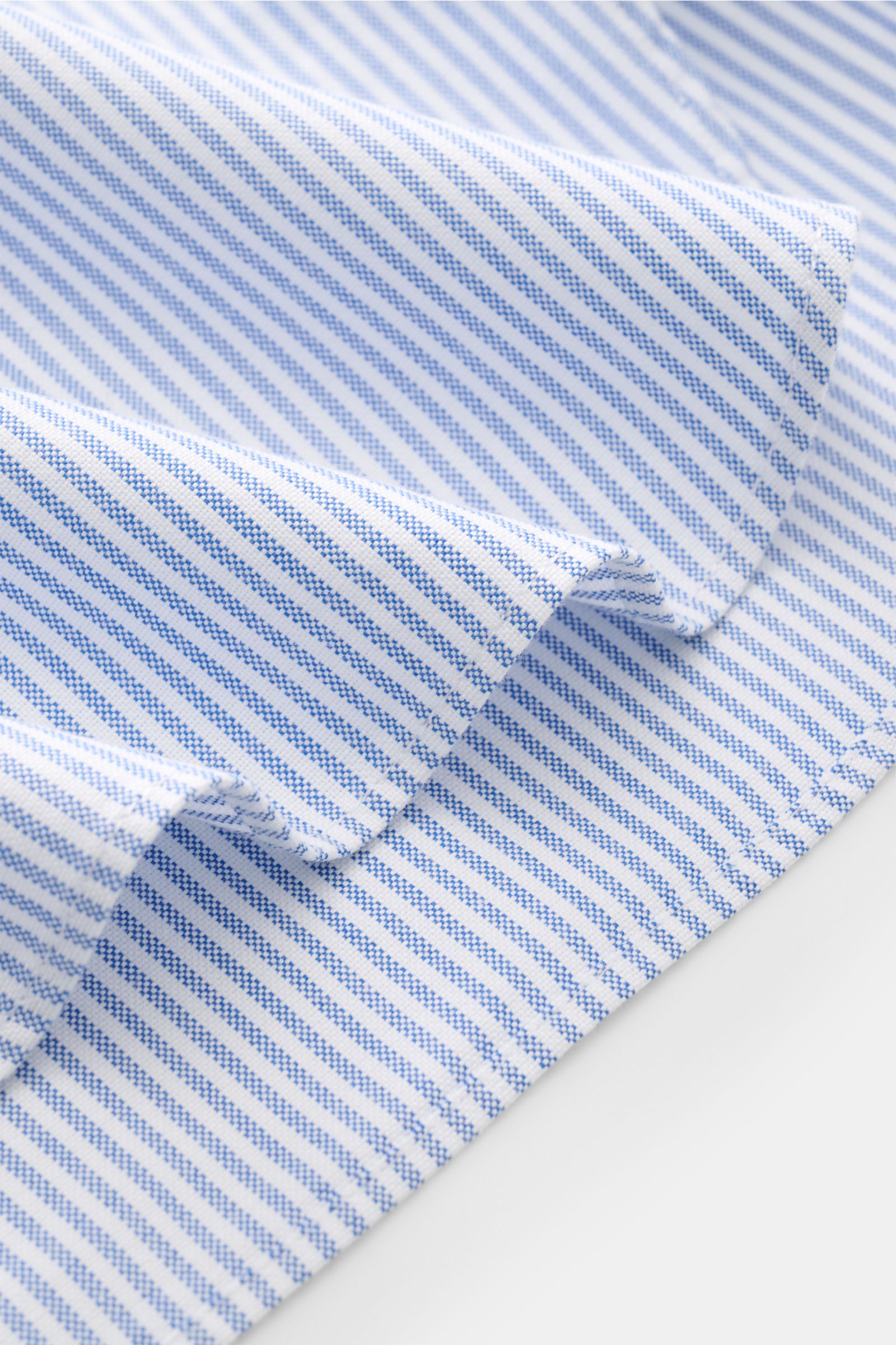 Close-up, angled view of the Golden Goose Oxford-Hemd Kent-Kragen blau/weiß gestreift showing blue and white striped cotton fabric with a textured, slightly rough feel.

Modernes Essential mit Signature-Attitüde: Das Baumwollhemd von GOLDEN GOOSE ergän