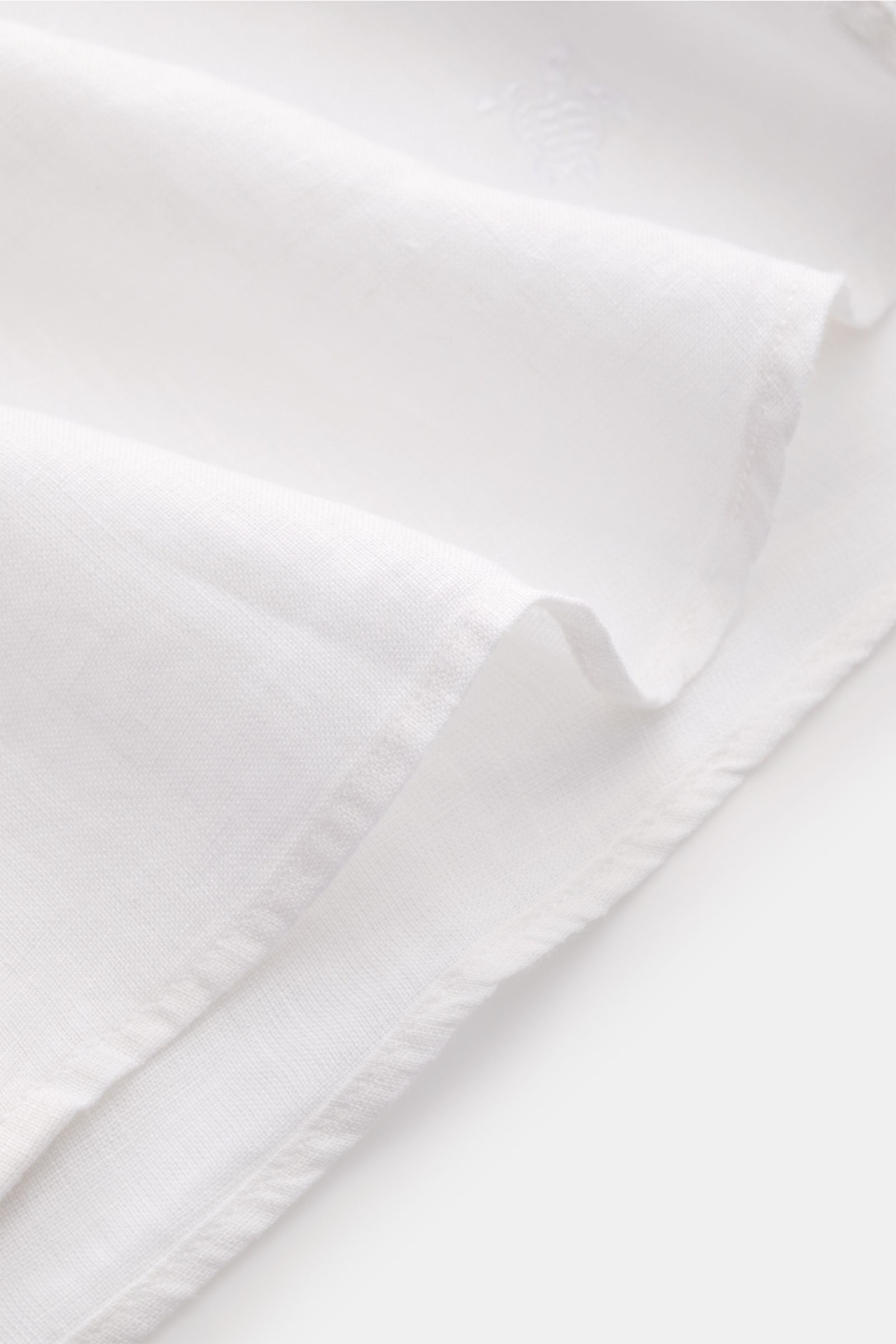 Vilebrequin Leinenhemd schmaler Kragen weiß, Detailaufnahme von Saum und Stoff, leichte Qualität, weicher Griff, Regular Fit, französische Knopfleiste, klassische Sportmanschette, aufgesetzte Brusttasche, gerundeter Saumverlauf mit tonalem Stitching.