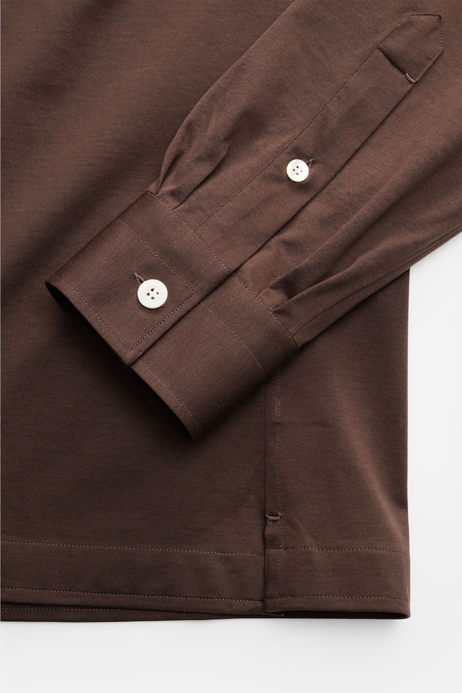 Nahaufnahme des braunen Giampaolo Jersey Popover-Hemd Haifisch-Kragen, seitliche Perspektive zeigt Sportmanschette, Perlmuttknöpfe, kurzen Saumschlitz, geraden Saumverlauf und glatten Baumwoll-Jersey.