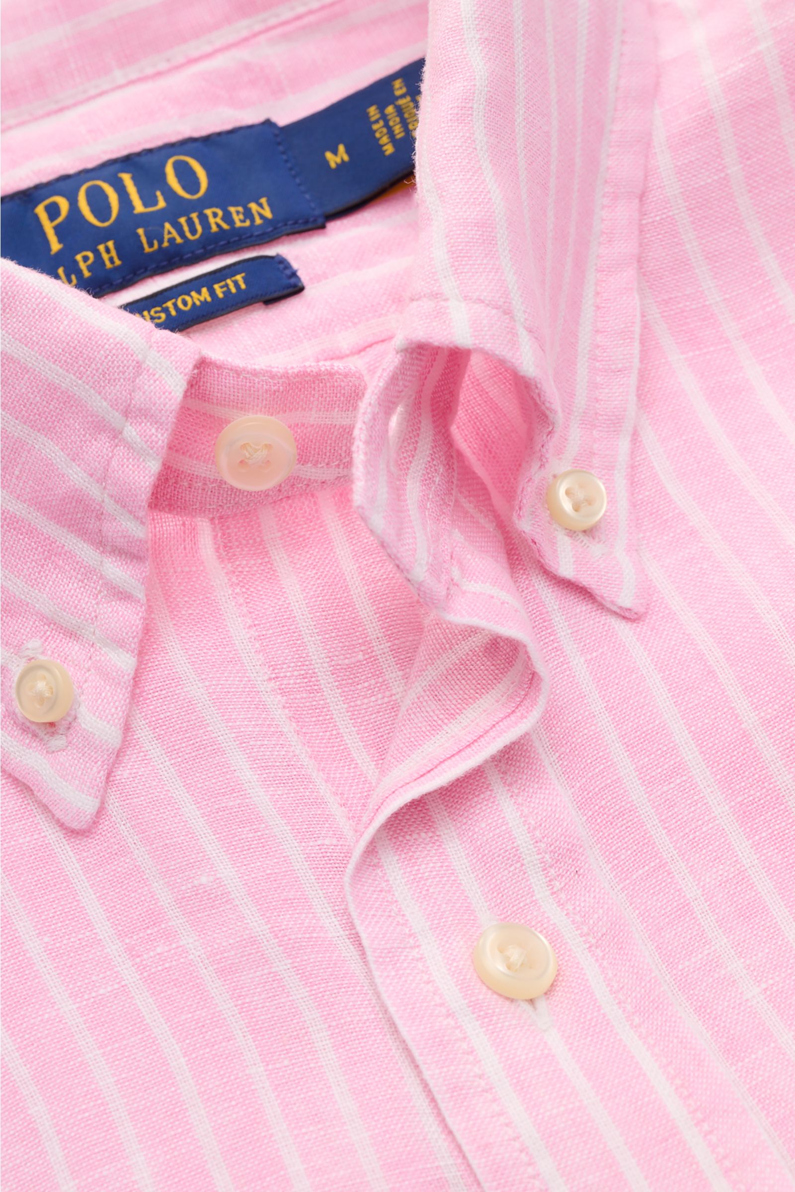 Nahaufnahme aus schräger Perspektive eines Polo Ralph Lauren Chambray-Leinenhemd Button-Down-Kragen rosé/weiß gestreift mit weichem Griff, Custom Fit, Knopfleiste und Polospieler-Stitching.