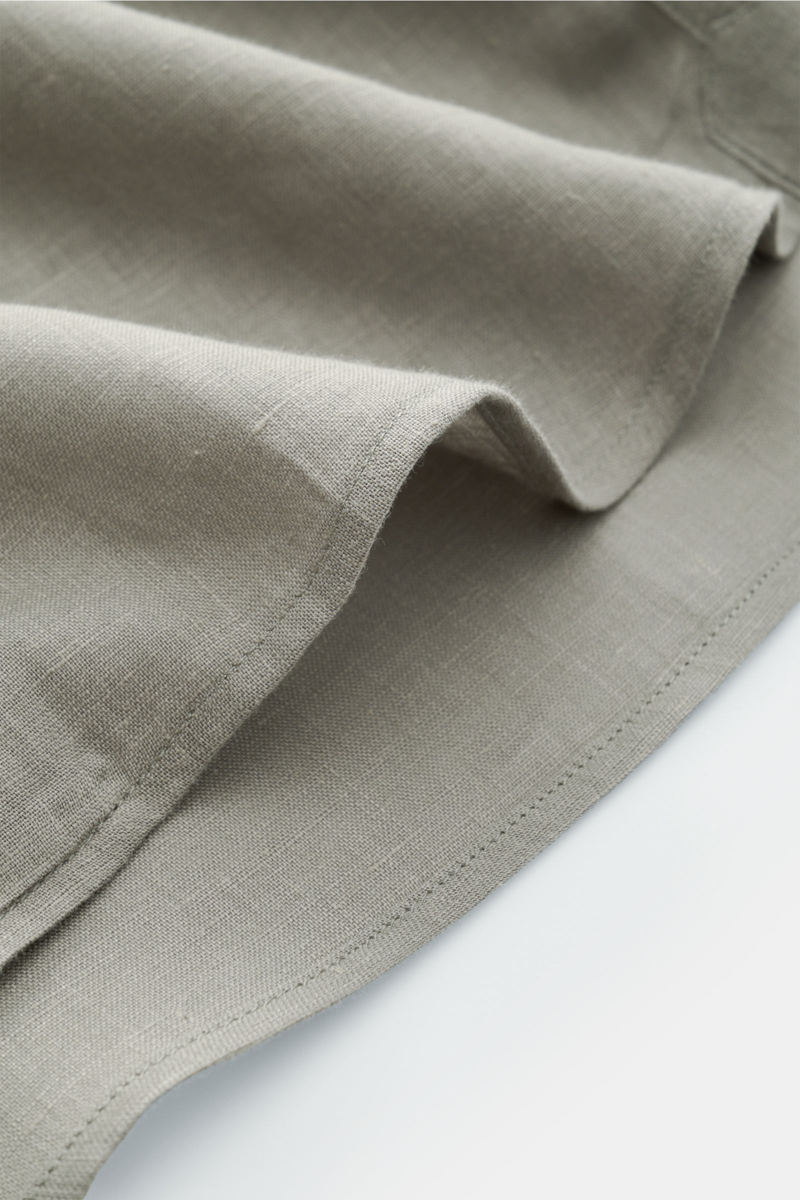 Close-up front-side view of the Brunello Cucinelli Leinenhemd Haifisch-Kragen salbei showing the fine linen fabric texture and hem detail.

Feinste Leinenqualität: Das sommerlich-leichte Hemd mit Haifischkragen aus dem Hause BRUNELLO CUCINELLI überzeug