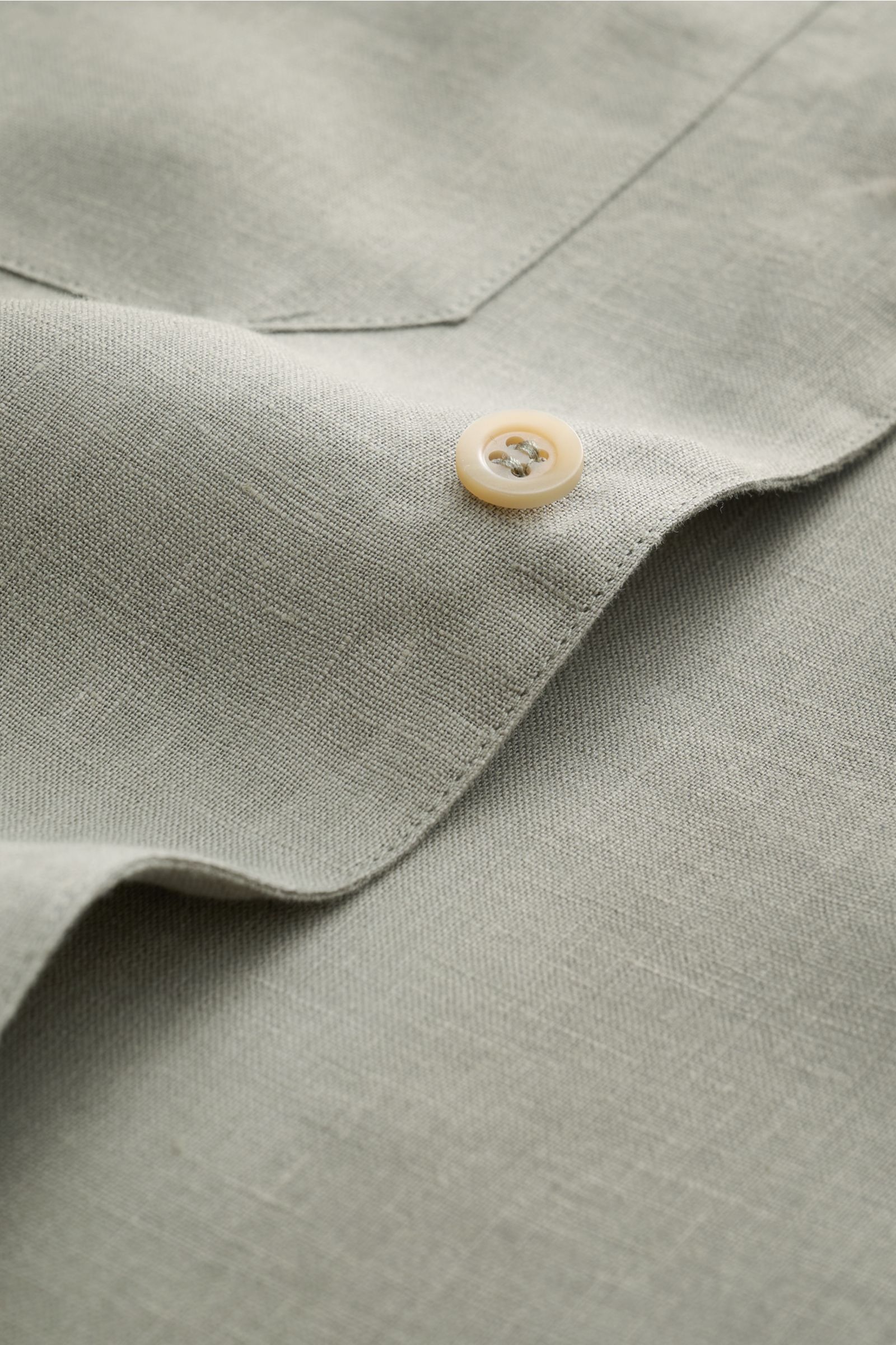Close-up front view of Brunello Cucinelli Leinenhemd Haifisch-Kragen salbei in fine sage linen with button and pocket details, showcasing linen texture.

Feinste Leinenqualität: Das sommerlich-leichte Hemd mit Haifischkragen aus dem Hause BRUNELLO CUCI