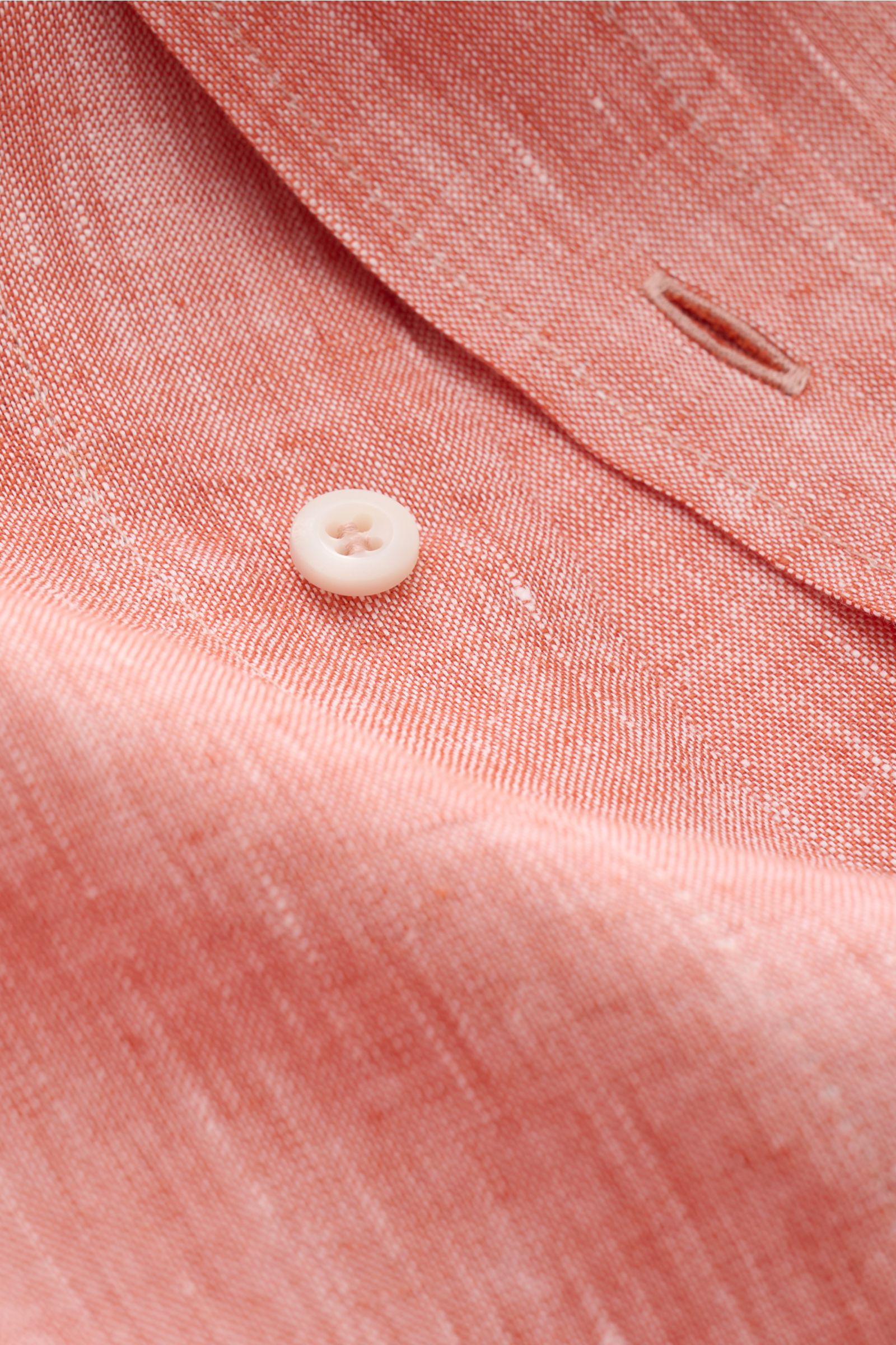 Close-up image of the Brunello Cucinelli Leinenhemd Haifisch-Kragen hellrot meliert, showing fabric texture, button, and buttonhole from an angled top view. Feinste Leinenqualität: Das sommerlich-leichte Hemd mit Haifischkragen aus dem Hause BRUNELLO C
