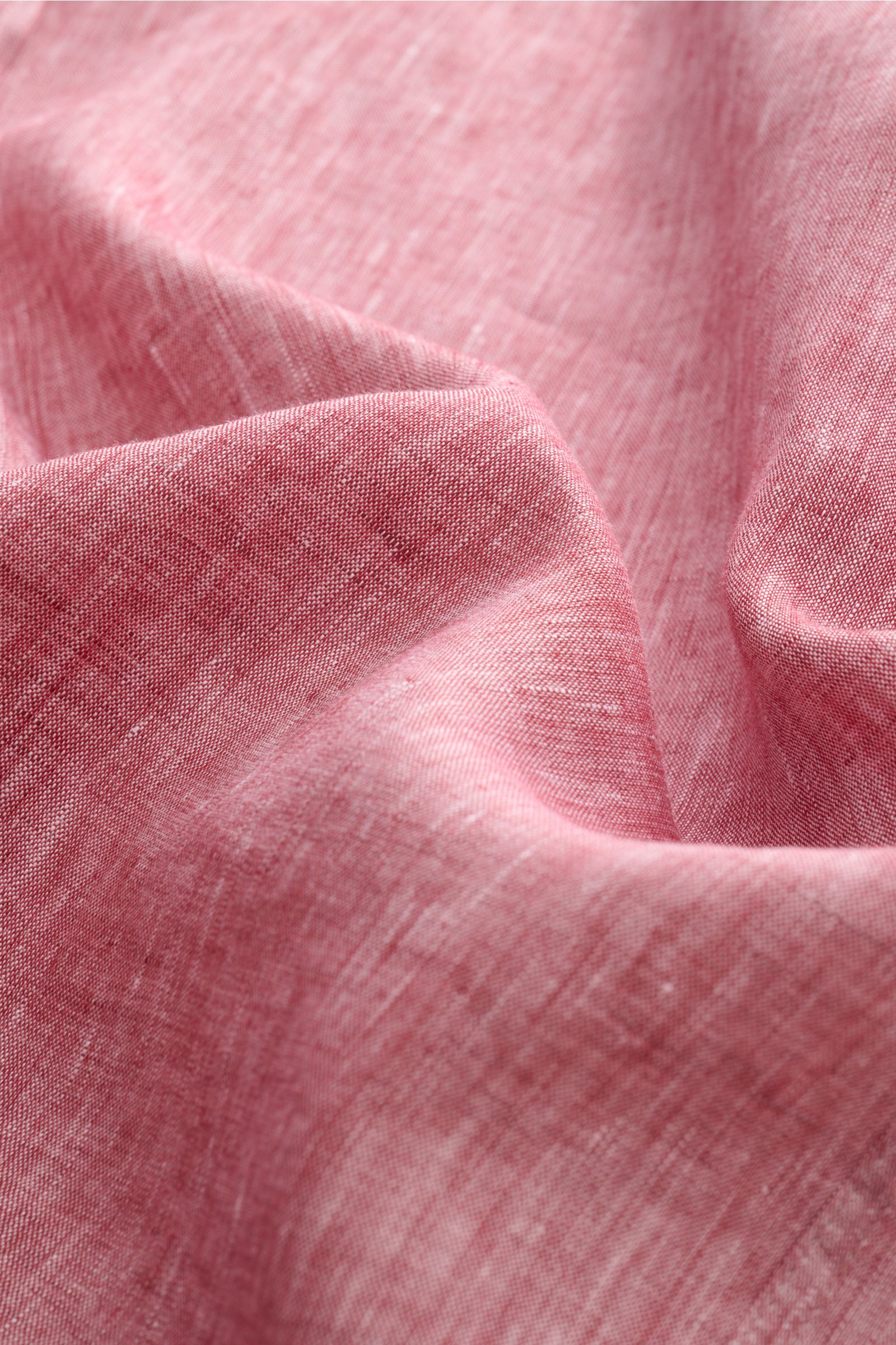 Close-up fabric detail of Brunello Cucinelli Leinenhemd Haifisch-Kragen rot meliert, showing pure linen texture in a red melange, photographed from above. Feinste Leinenqualität: Das sommerlich-leichte Hemd mit Haifischkragen aus dem Hause BRUNELLO CUC