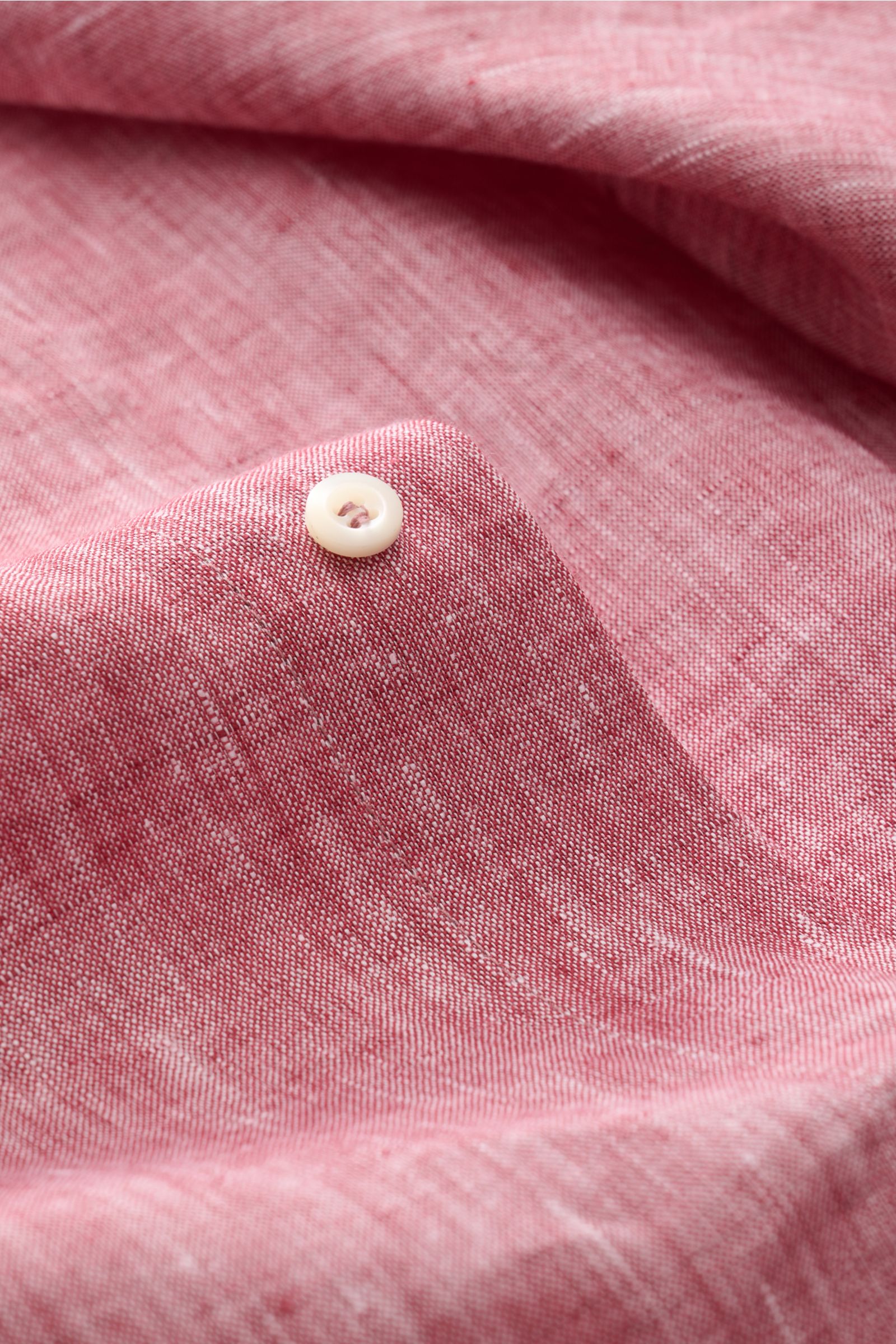 Close-up of Brunello Cucinelli Leinenhemd Haifisch-Kragen rot meliert fabric and white pearl button, photographed from a top angle.

Description: Feinste Leinenqualität: Das sommerlich-leichte Hemd mit Haifischkragen aus dem Hause BRUNELLO CUCINELLI üb