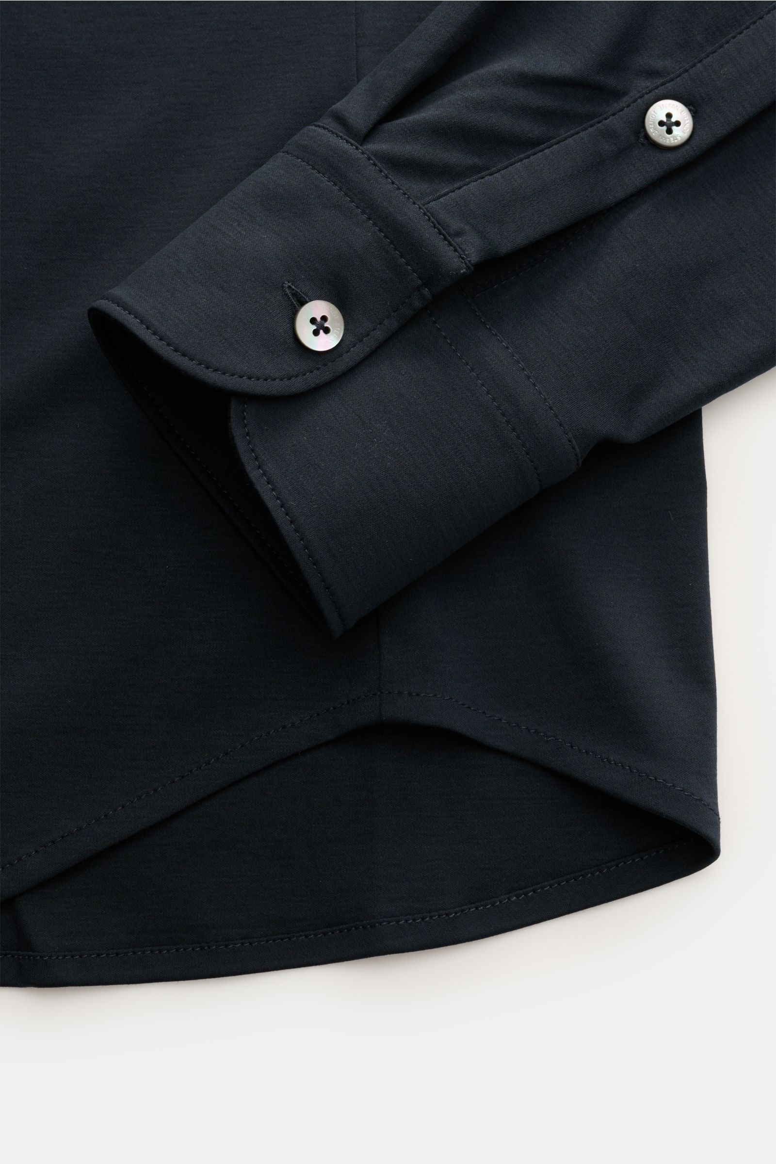 Nahaufnahme des Ärmelabschlusses mit klassischer Sportmanschette und Perlmuttknopf sowie gerundetem Saum vom Stefan Brandt Jersey-Hemd 'Otis' Haifisch-Kragen navy aus flexibler Pima-Baumwolle, Slim Fit, glattem Griff, französischer Knopfleiste.