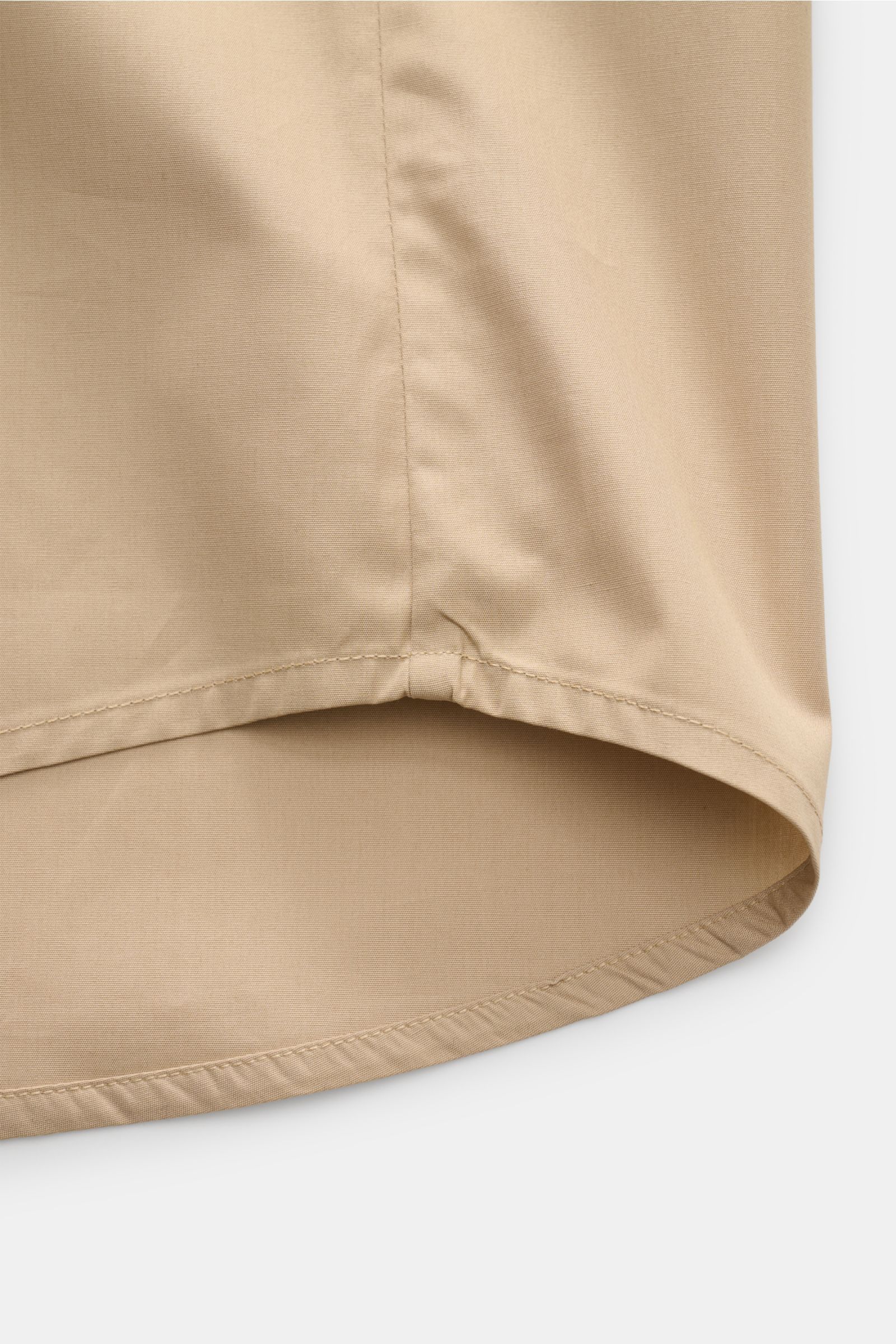 Close-up view of the hem of the A.P.C. Kurzarmhemd Kent-Kragen sand, showcasing the slightly rounded hemline and smooth cotton fabric.