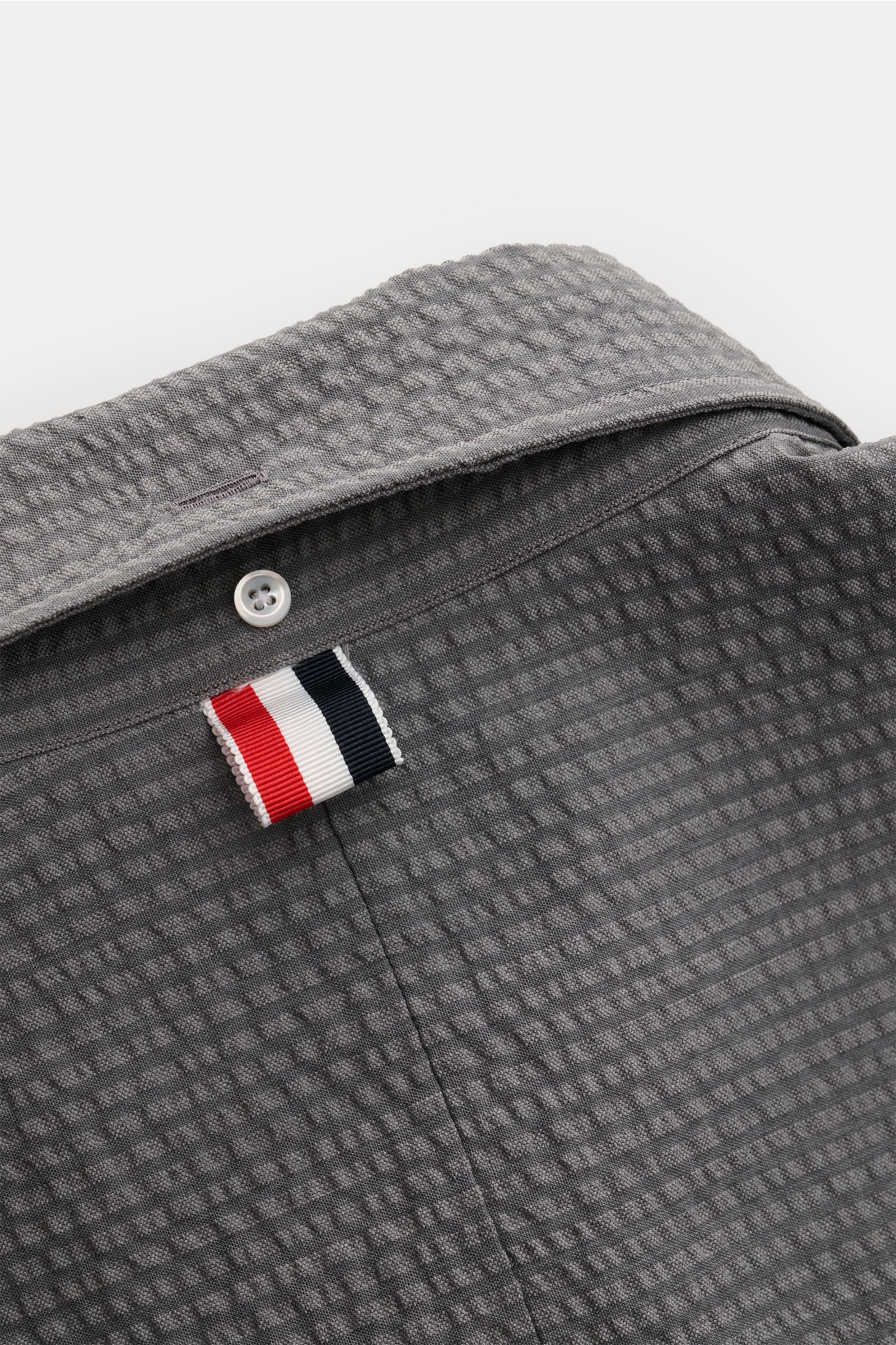 Thom Browne Seersucker-Kurzarmhemd Button-Down-Kragen dunkelgrau, Nahaufnahme von Rücken mit Wolle-Struktur und markantem Weblabel.