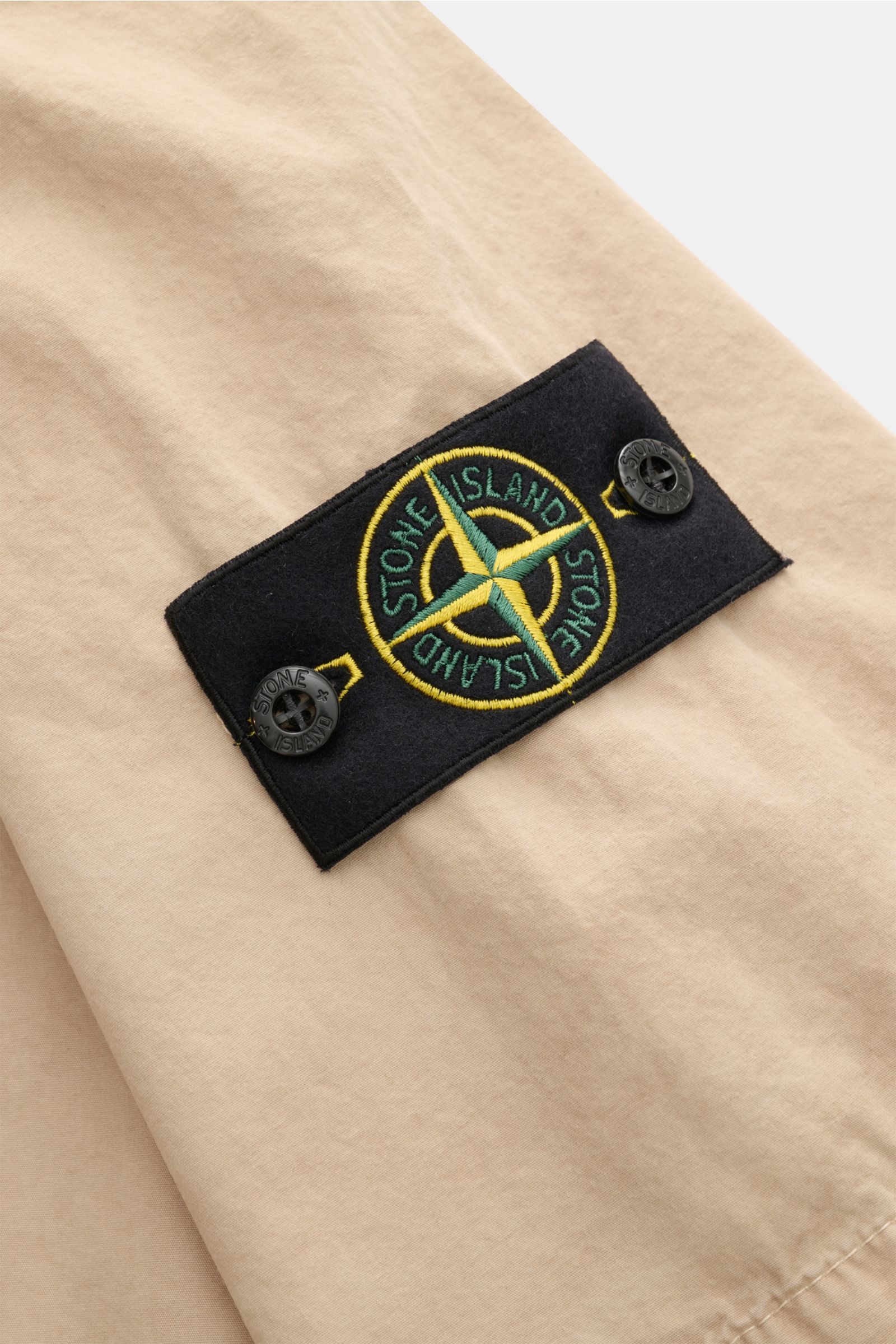 Stone Island Kurzarmhemd 'Brushed Canvas' Kent-Kragen beige, Detailaufnahme des Kompass-Badges am Oberarm in weicher Bio-Baumwolle.