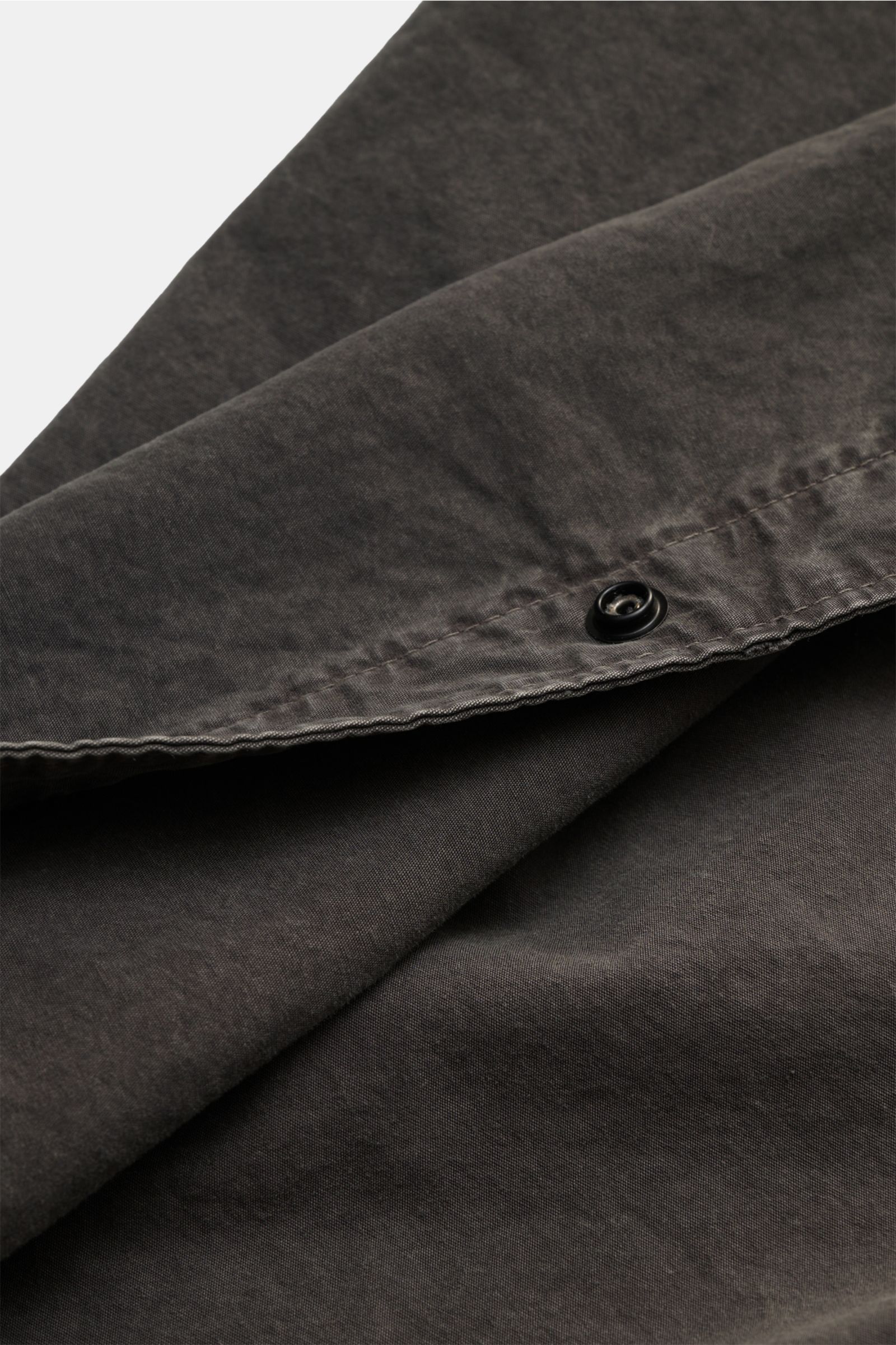 Close-up of Stone Island Short sleeve shirt 'Brushed Canvas' Kent collar anthracite showing soft organic cotton fabric, a concealed snap button, and garment-dyed texture from a top side angle. Versatility and urban style: This short sleeve shirt by STONE 