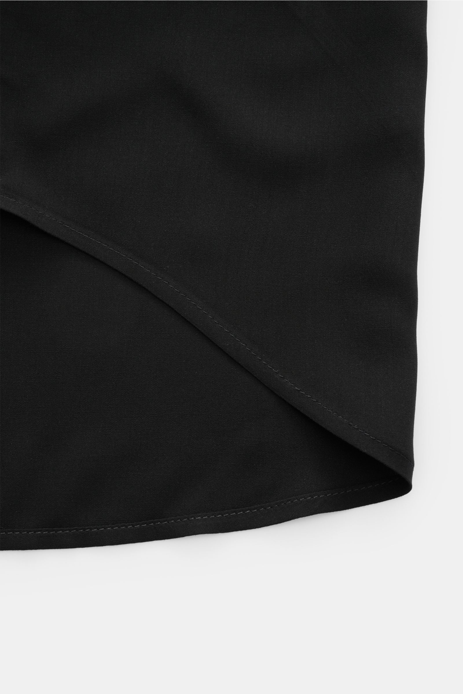 Close-up view of the rounded hem of the Ami Paris Short sleeve shirt 'Boxy' Cuban collar black, showcasing pure viscose fabric with soft feel, oversized fit, French button placket, and logo stitching; modern and casual, a key piece for spring and summer.