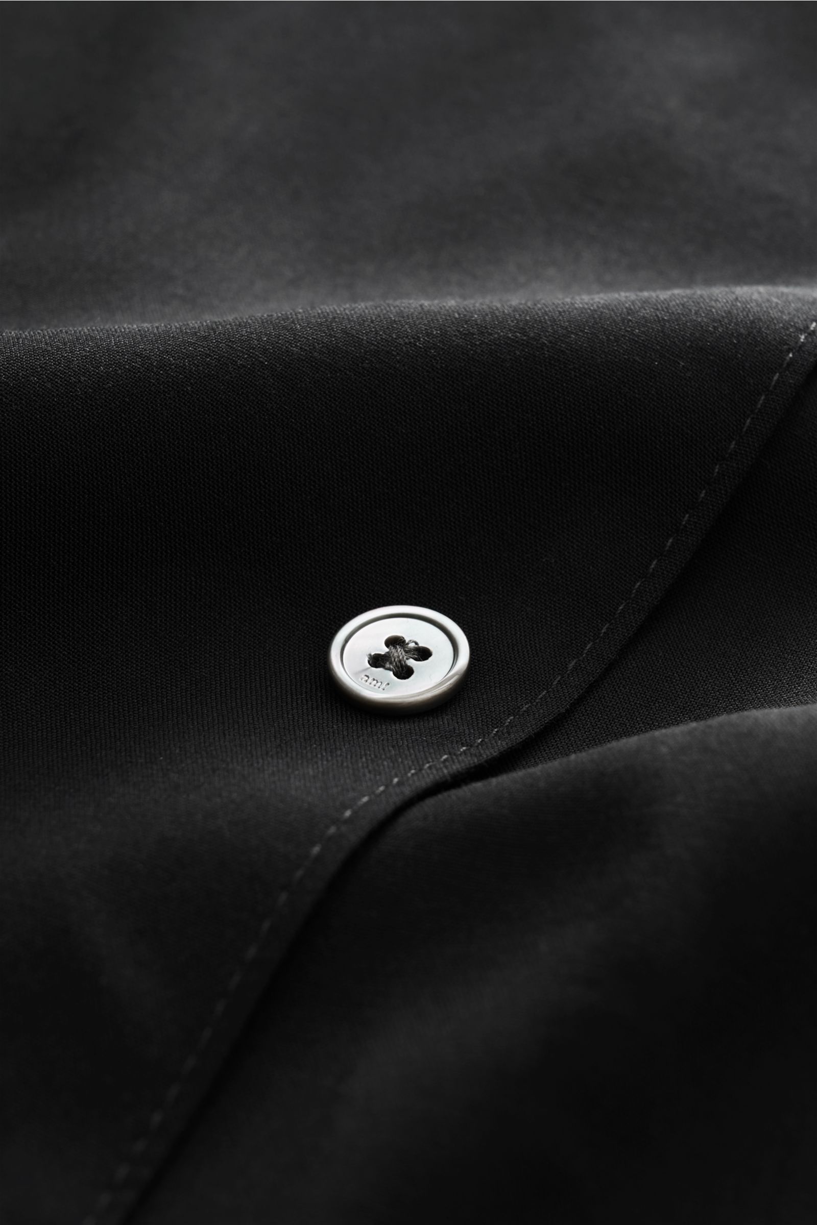 Close-up front view of Ami Paris Short sleeve shirt 'Boxy' Cuban collar black showing pure viscose fabric, French button placket, logo stitching, soft feel, oversized fit, and rounded hem. Modern and casual: With its 'Boxy' fit, this short sleeve shirt by