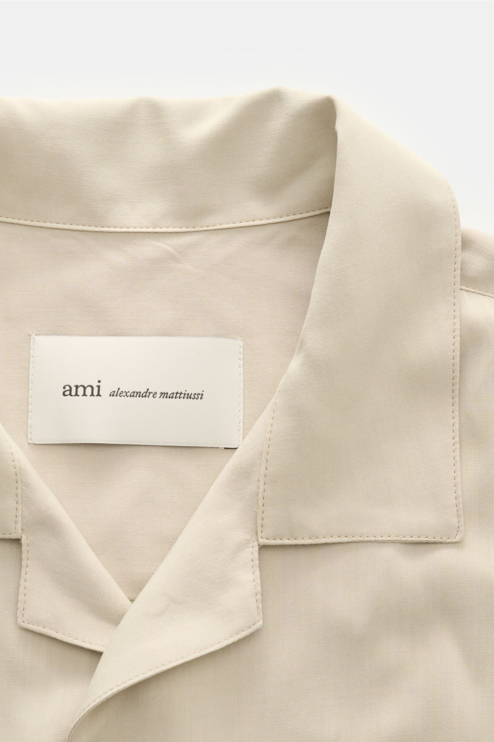Close-up front view of Ami Paris Kurzarmhemd 'Boxy' Kubanischer Kragen sand, a modern, oversized short-sleeve shirt with a Cuban collar.

Modern und lässig: Mit seinem 'Boxy' Fit wird das Kurzarmhemd von AMI PARIS zum unkomplizierten Key-Piece für Früh