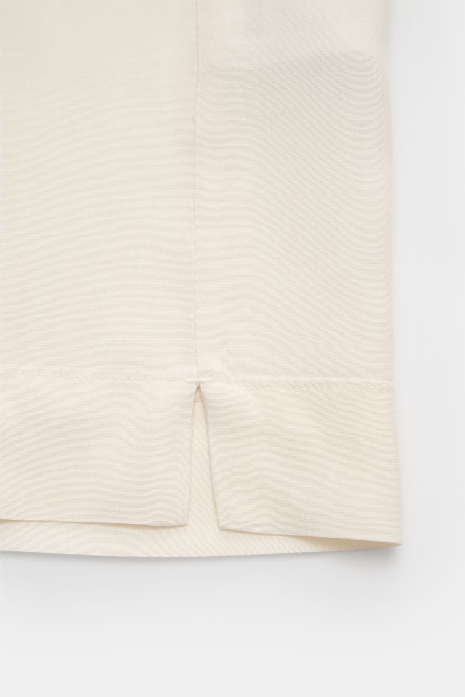 Nahaufnahme seitlicher Saumschlitz des cremefarbenen Ché Kurzarmhemds 'Valbonne' mit kubanischem Kragen aus fließender Viskose