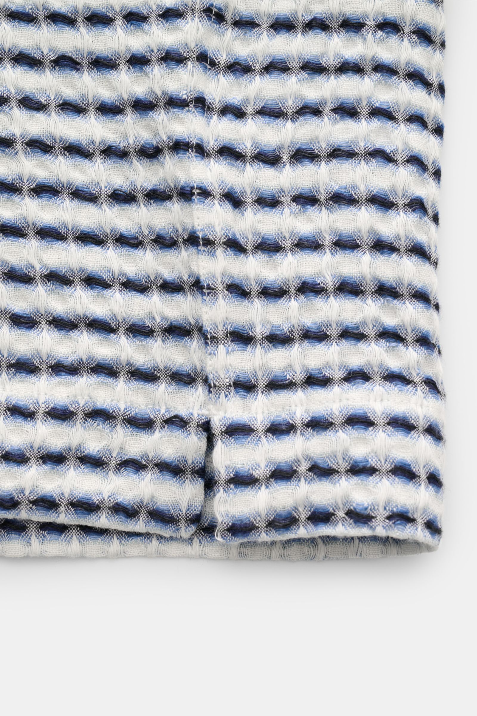 Close-up front view of the fabric and sleeve hem of the Ché Leinen-Kurzarmhemd 'Riita' Kubanischer Kragen blau/weiß gemustert, showing the intricate waffle piqué texture with blue, white, and black pattern. 

Description: Im Sommer kreiert das Leinen-K