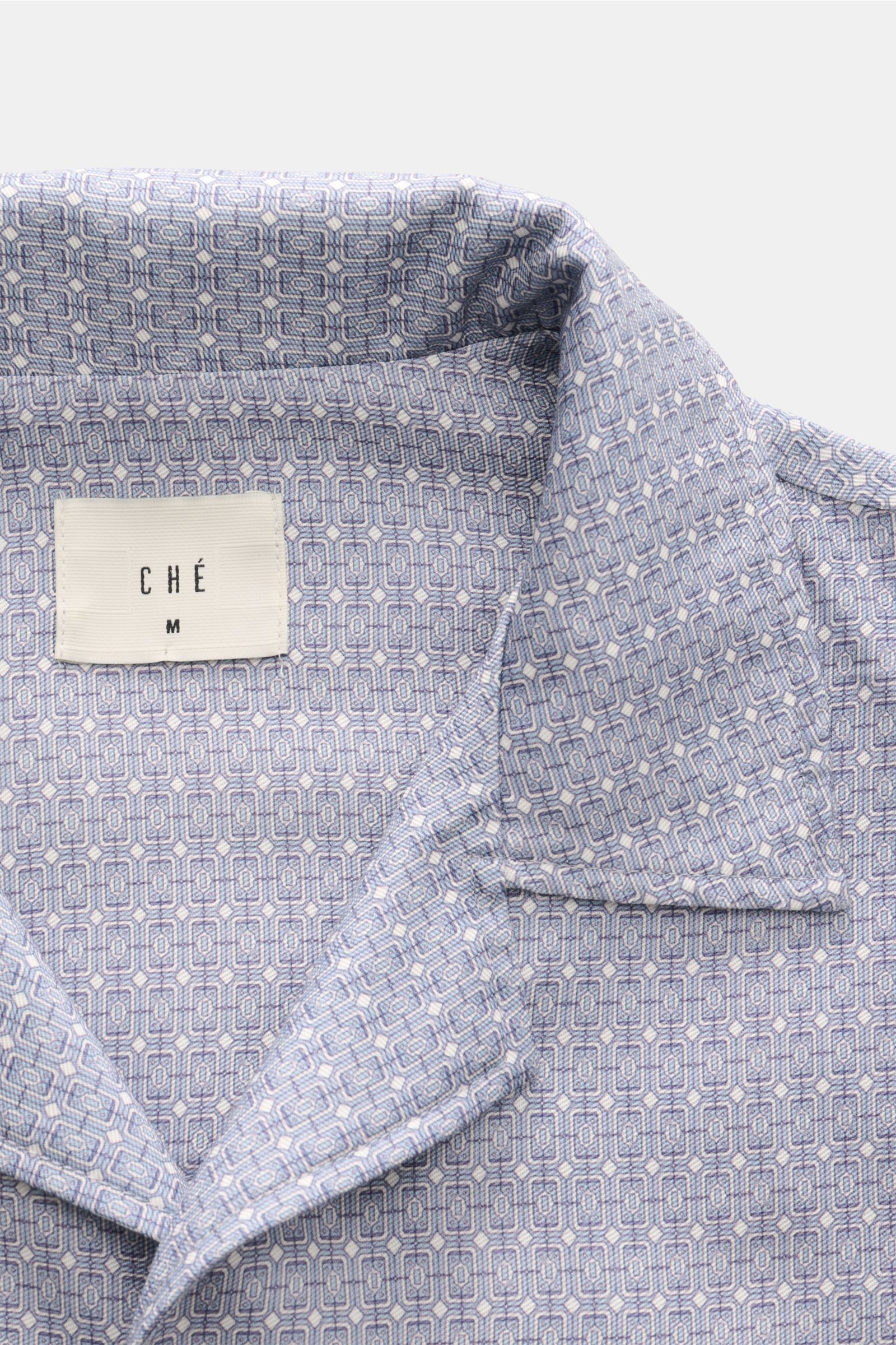 Ché Kurzarmhemd 'Lucena' Kubanischer Kragen rauchblau/offwhite gemustert, close-up front view showing ornamental print, collar, and fabric texture. Das Kurzarmhemd 'Lucena' von CHÉ zieht mit ornamentalem Print, fließendem Lyocell und entspannter Oversi
