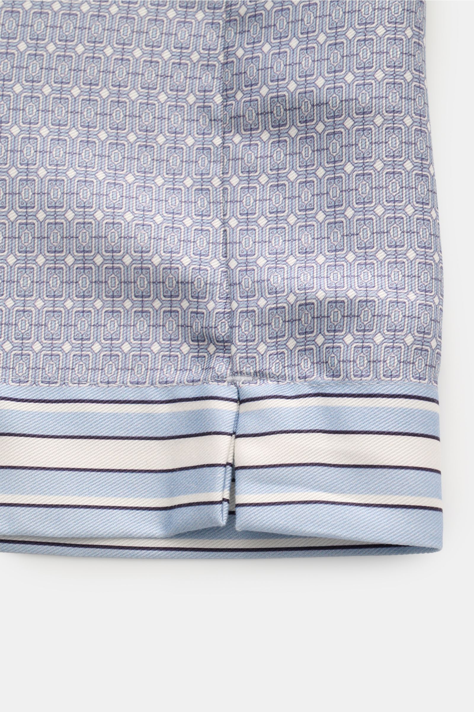 Ché Kurzarmhemd 'Lucena' Kubanischer Kragen rauchblau/offwhite gemustert shown close-up from the front hem, featuring ornamental print, smooth lyocell fabric, and side hem slit. Das Kurzarmhemd 'Lucena' von CHÉ zieht mit ornamentalem Print, fließendem 