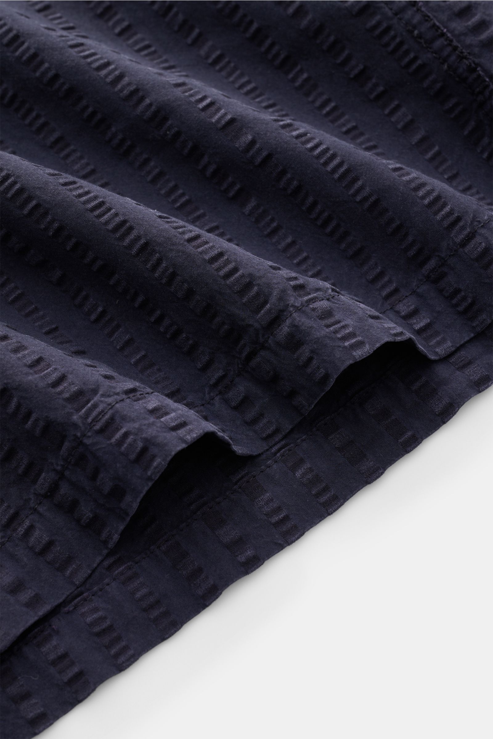 Close-up angled view of the navy blue Officine Générale Short sleeve shirt 'Eren' Cuban collar navy showing lightweight seersucker texture, straight hem, and slightly textured lyocell-cotton blend fabric.