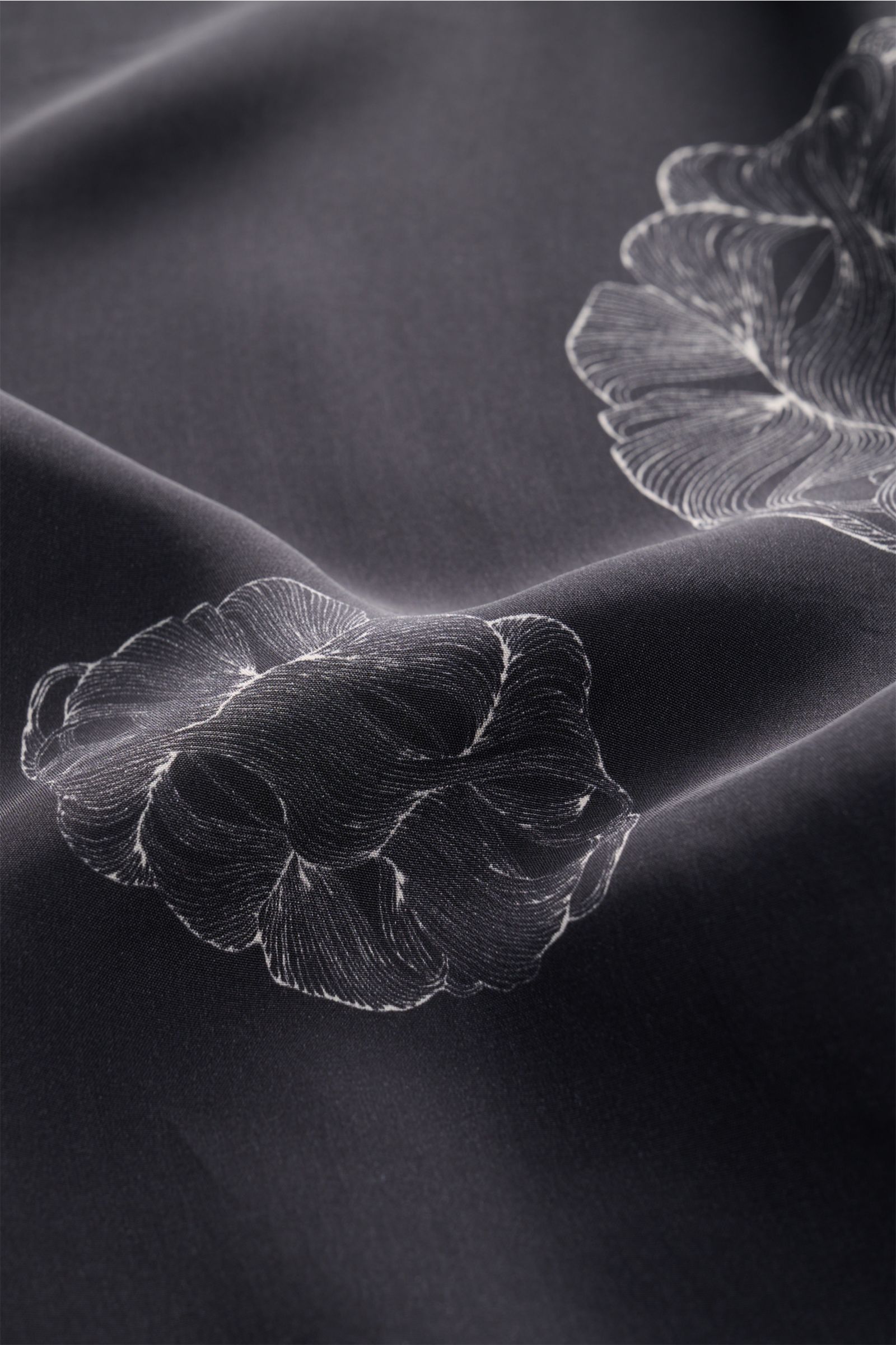 Close-up view of the fabric of the Officine Générale Short-sleeved shirt 'Eren' Cuban collar black patterned, showing detailed floral print on lightweight pure viscose material. Get a casual look for warm days: The short-sleeved shirt 'Eren' by OFFICINE G