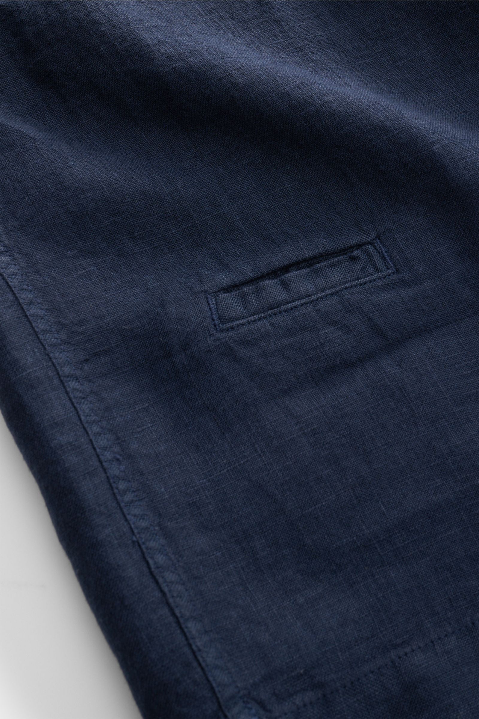 Nahaufnahme des dunkelblauen 04651/ A trip in a bag Leinen-Kurzarmhemd Kubanischer Kragen navy mit feiner Leinenstruktur, kleiner Münztasche und Saumdetail, fotografiert aus schräger Perspektive.