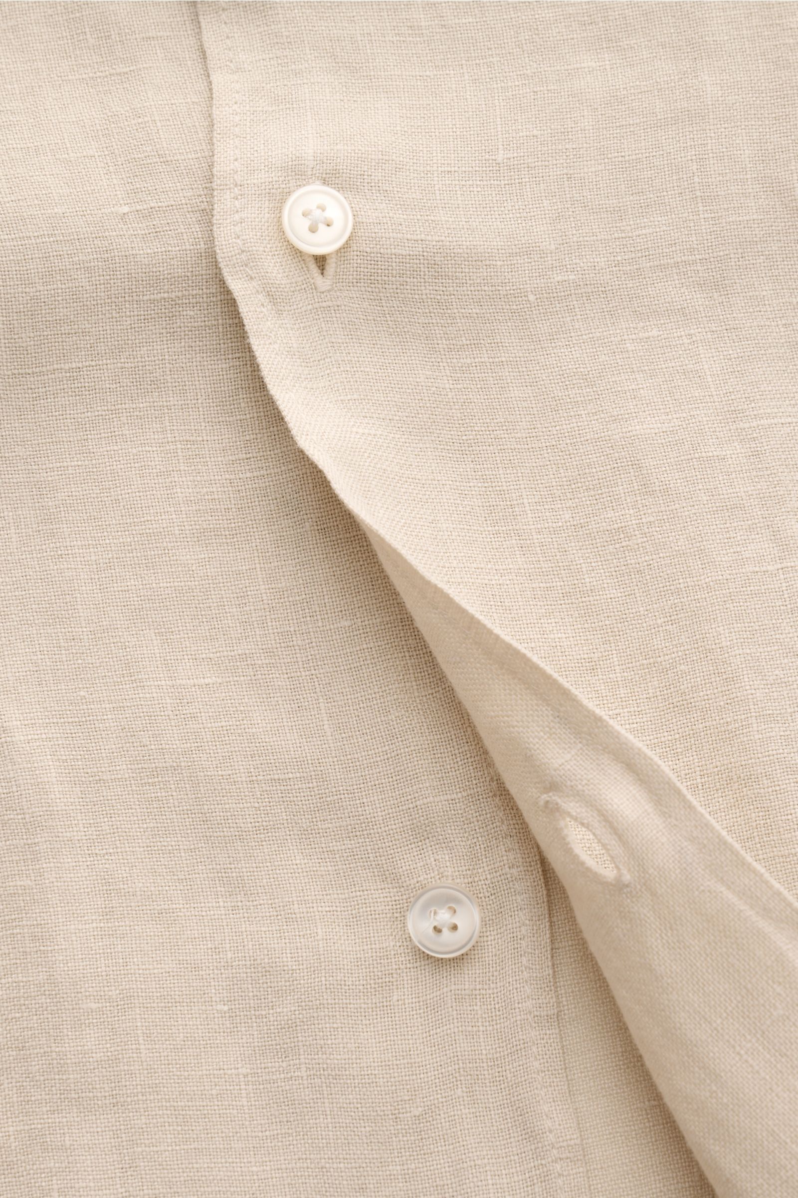 Nahaufnahme des beigen 04651/ A trip in a bag Leinen-Kurzarmhemd Kubanischer Kragen, Fokus auf Knöpfe und Leinenstruktur, luftig und leicht.